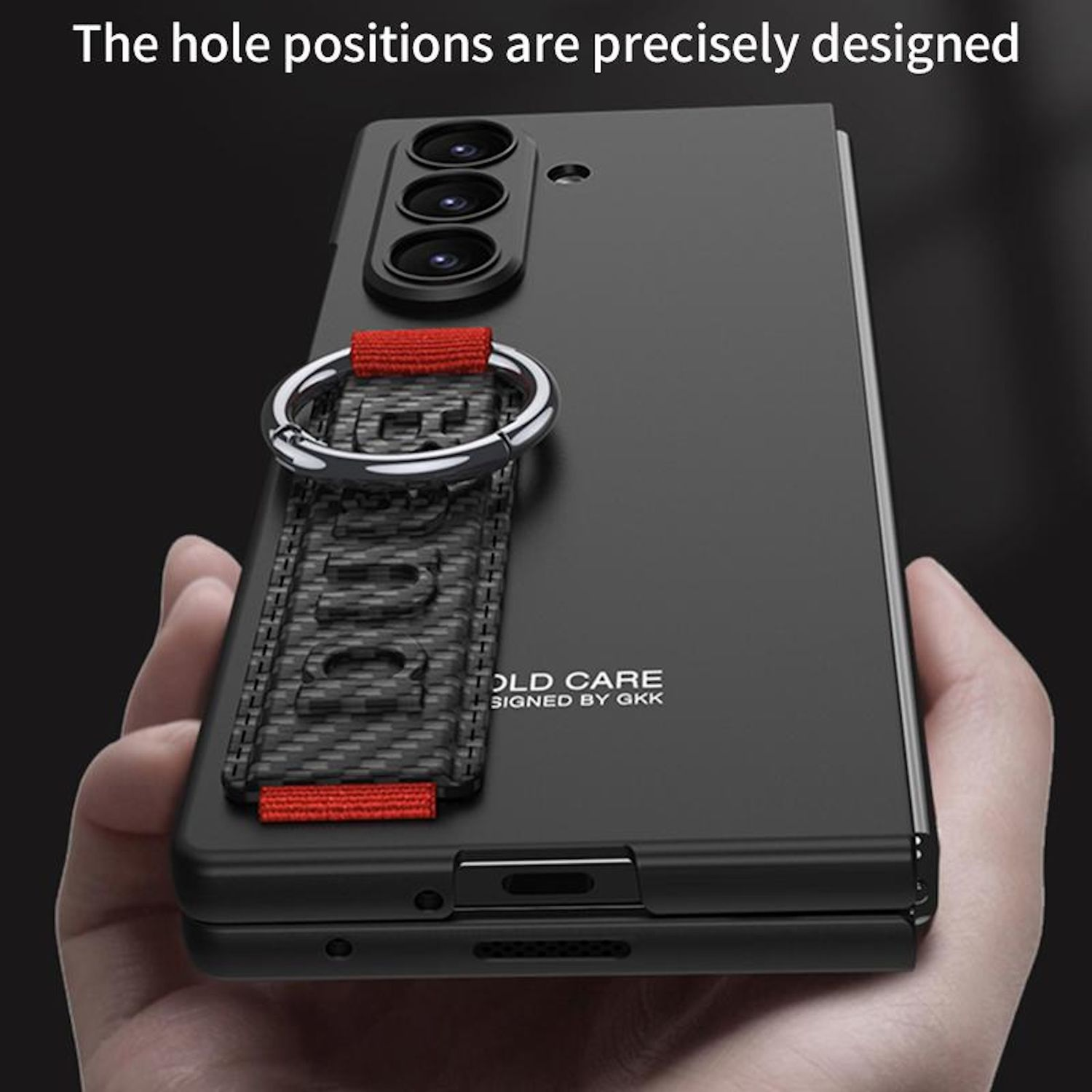 Funda negra para teléfono con correa roja y anillo plateado. El teléfono está abierto y sostenido en la mano de una persona.