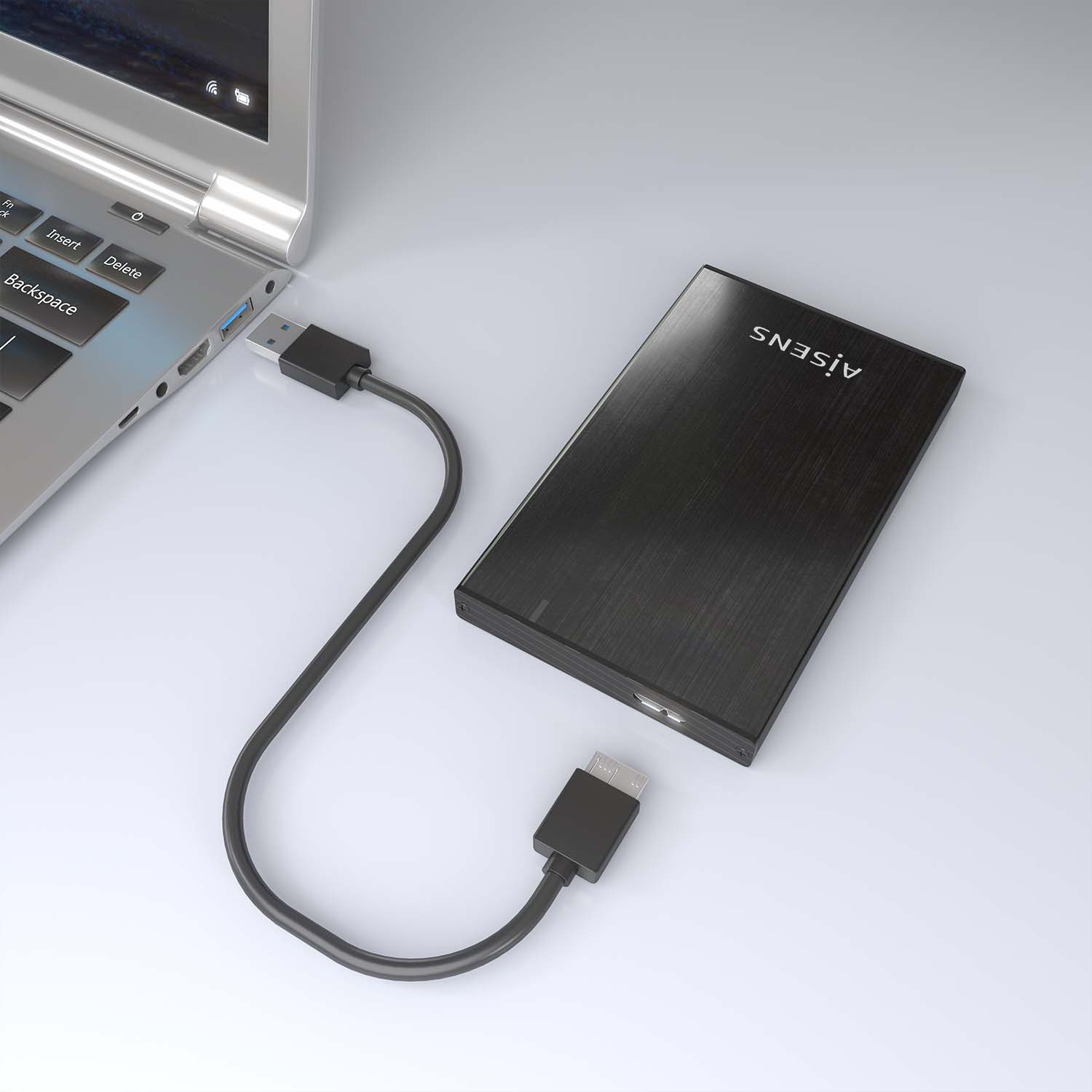 Laptop collegato a un disco rigido esterno nero. Sfondo bianco.
