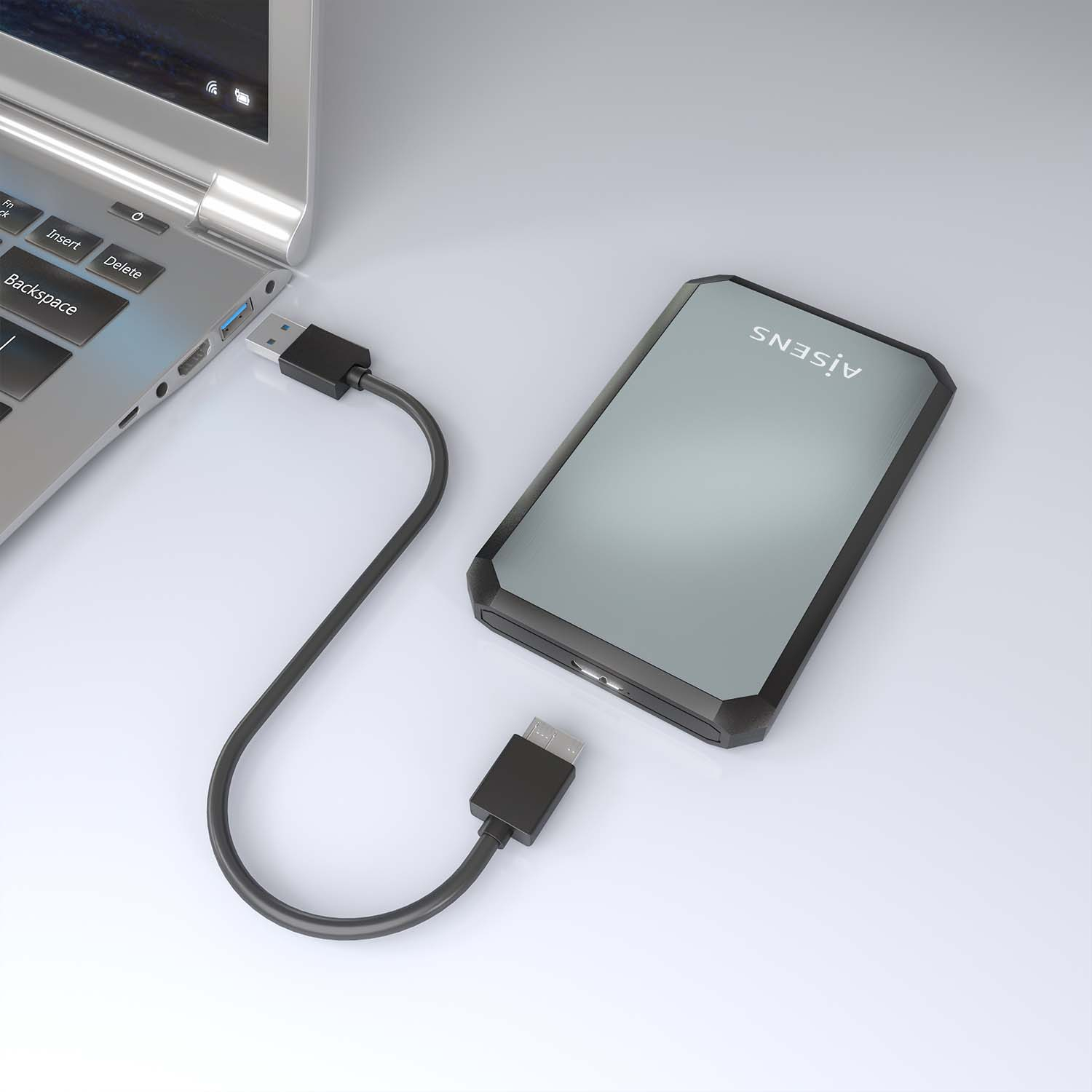 Un laptop è collegato a un disco rigido esterno nero tramite un cavo USB. Il disco rigido ha una finitura argentata. Sfondo bianco.