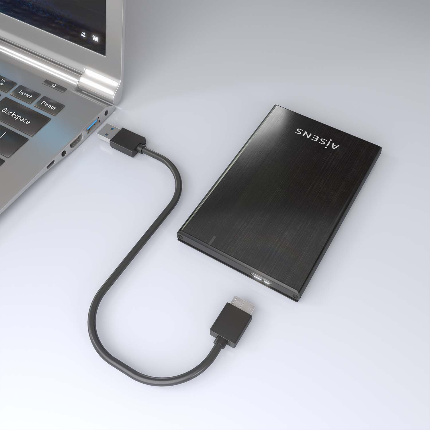 Un laptop è collegato a un disco rigido esterno nero tramite un cavo USB. Il disco rigido ha una finitura nera. Sfondo bianco.