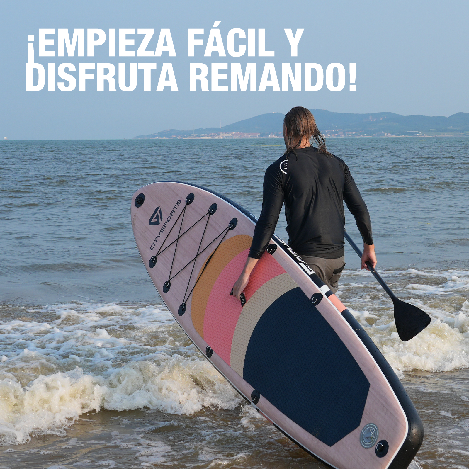 Un hombre con pelo largo entra en el agua con una tabla de paddle surf. El texto "¡EMPIEZA FÁCIL Y DISFRUTA REMANDO!" está arriba.
