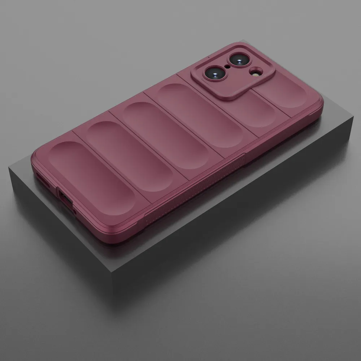 Une coque de téléphone bordeaux sur une surface grise, avec des rainures verticales et des découpes pour la caméra.