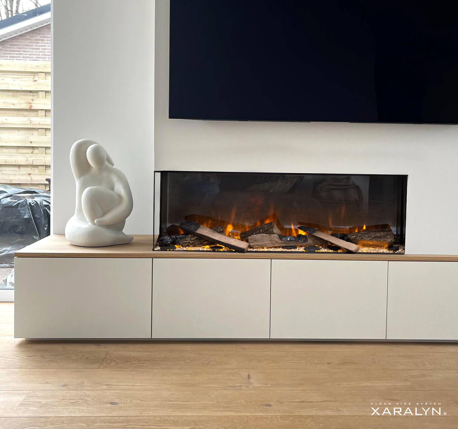 Een open haard met een wit frame en een zwart interieur. Een sculptuur staat links.