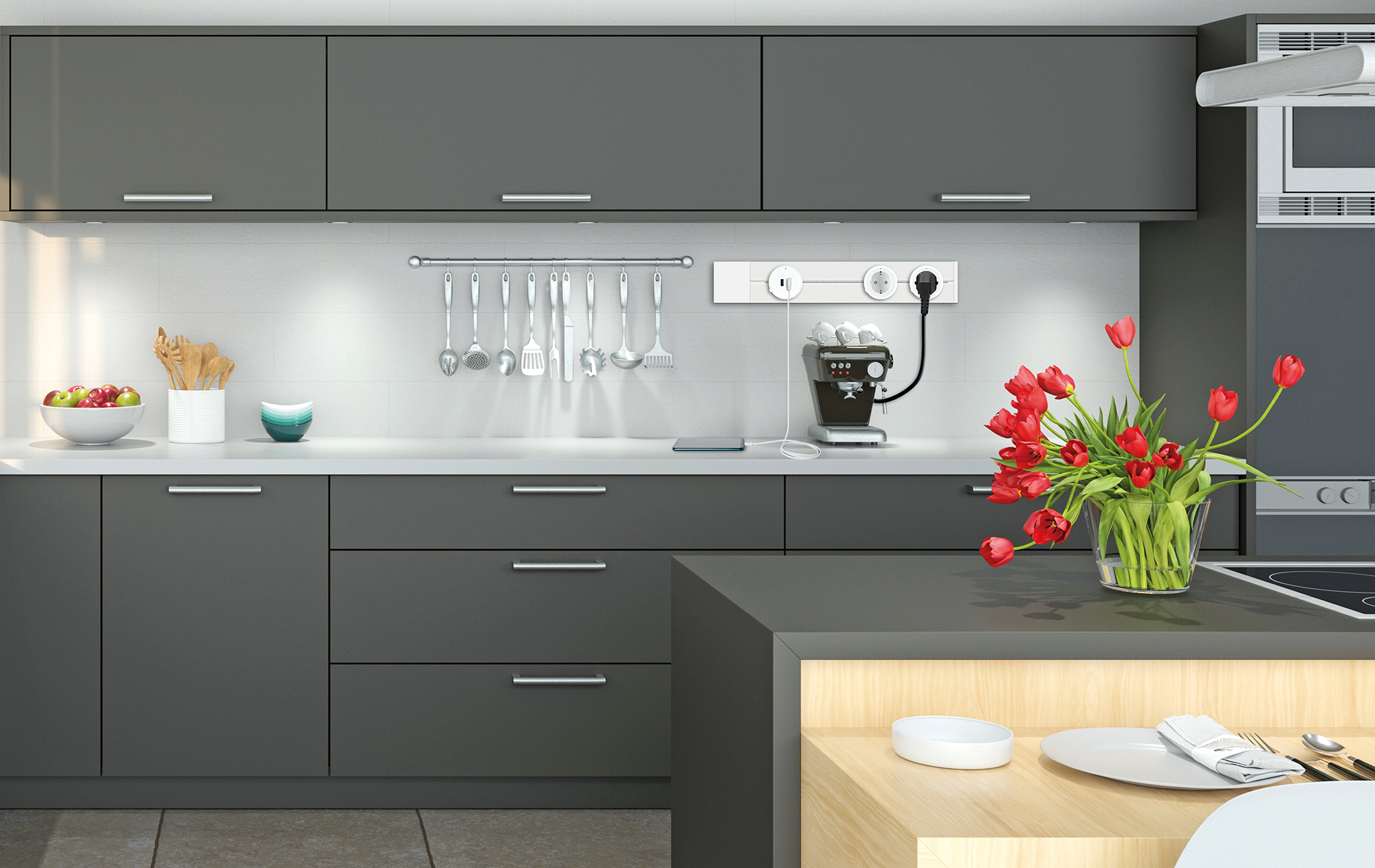 Moderne Küche mit dunkelgrauen Schränken, weißen Arbeitsplatten und einer Vase mit roten Tulpen. Kaffeemaschine und Utensilien sind sichtbar.