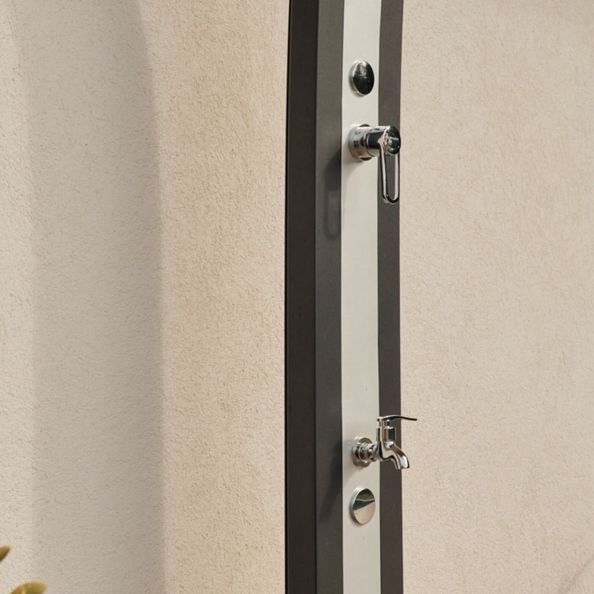 Grifo de ducha contra una pared texturizada. Tiene un marco oscuro con una franja blanca y accesorios metálicos.