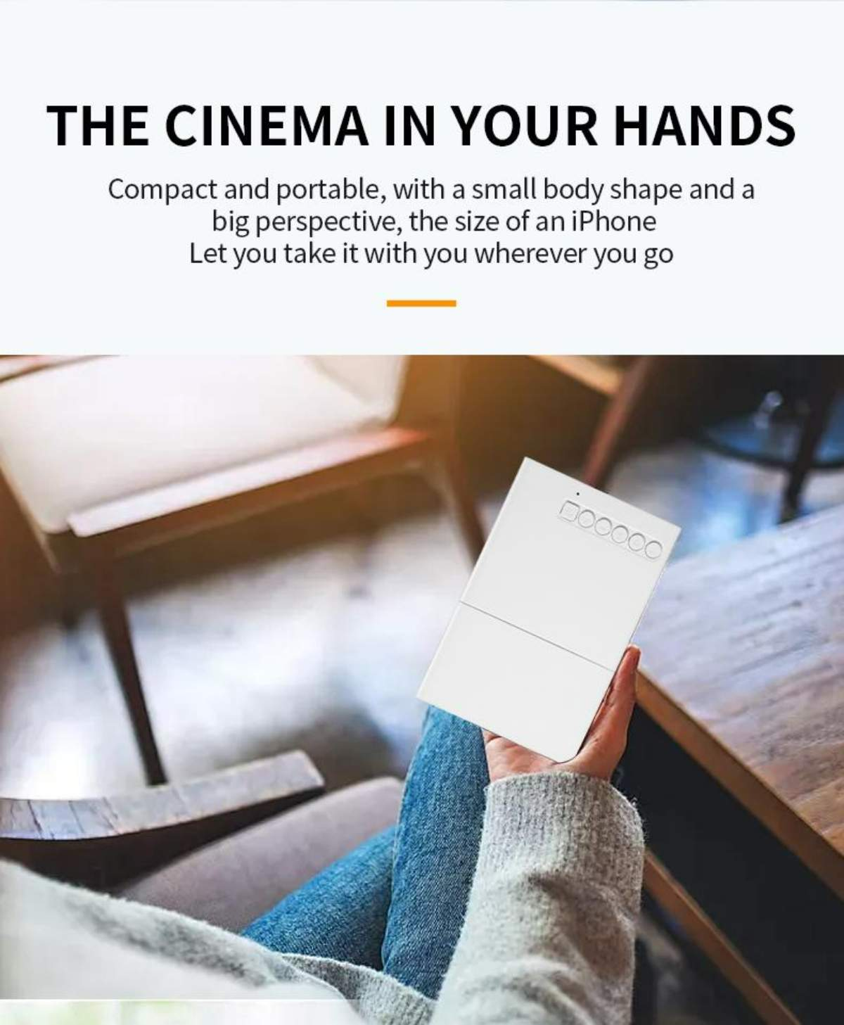 Eine Person hält ein weißes Gerät. Der Text darüber lautet 'THE CINEMA IN YOUR HANDS'. Die Person sitzt an einem Holztisch.