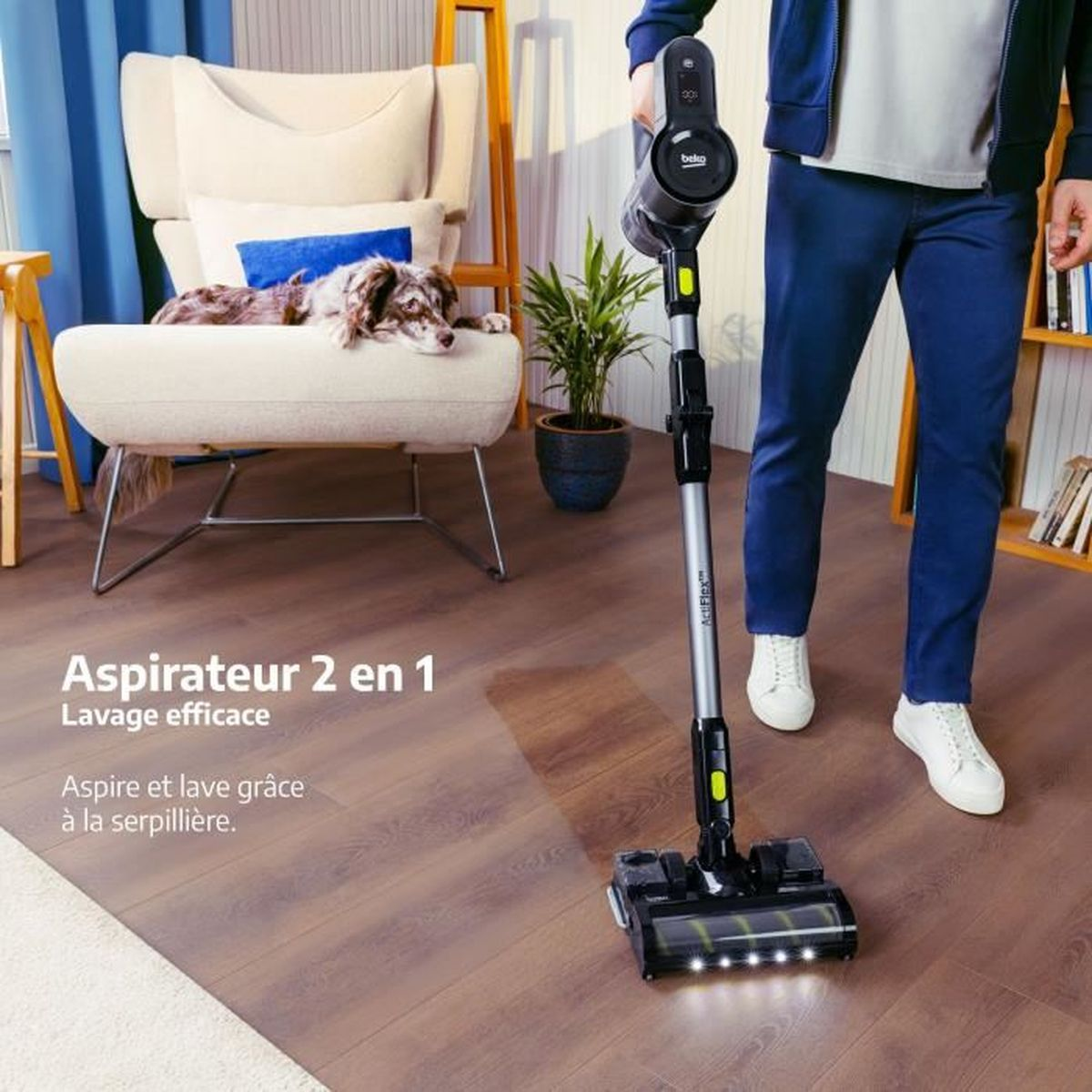 Una persona aspira un suelo de madera con una aspiradora Beko. Un perro descansa en un sillón beige. Texto: Aspirateur 2 en 1.
