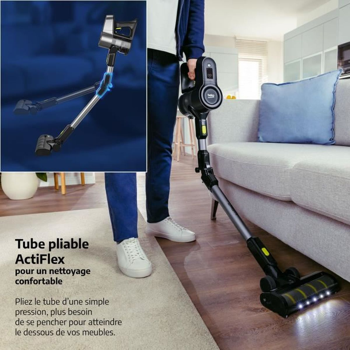 Una persona usa una aspiradora negra y plateada. La aspiradora tiene un tubo flexible. El fondo muestra un sofá y una alfombra.