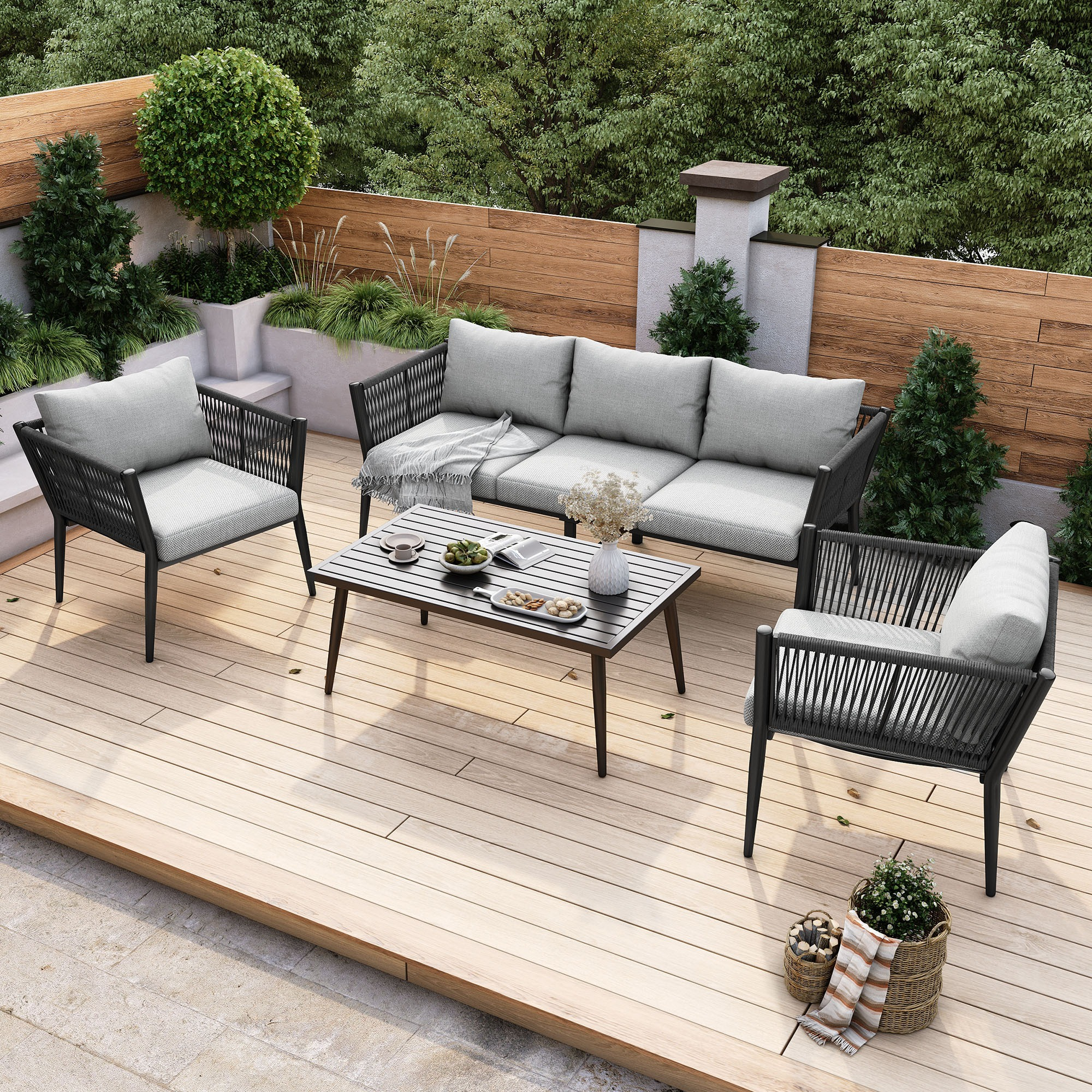Outdoor-Terrasseneinrichtung mit grauen Kissen auf schwarzen Möbeln. Ein Holzdeck mit Couchtisch und Pflanzen.