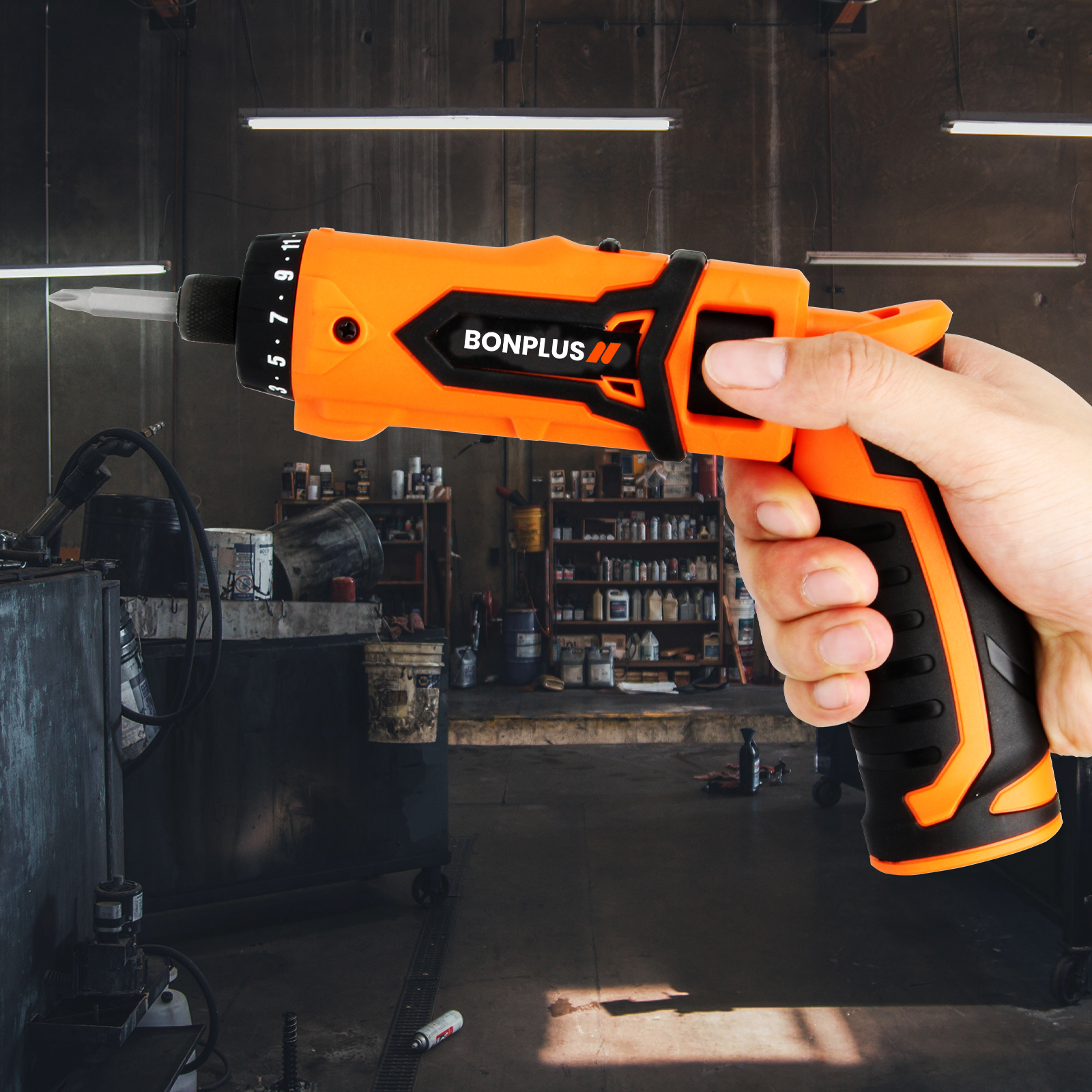 Mano sosteniendo un destornillador eléctrico Bonplus naranja y negro en un taller. El fondo muestra estantes con herramientas.