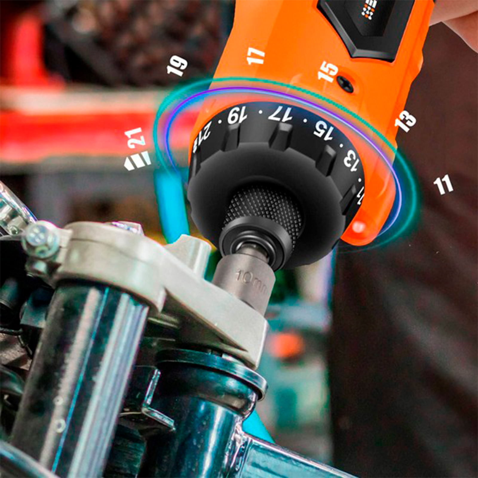 Un destornillador eléctrico naranja está sobre un componente de motocicleta. Tiene números. El enchufe está en el componente.