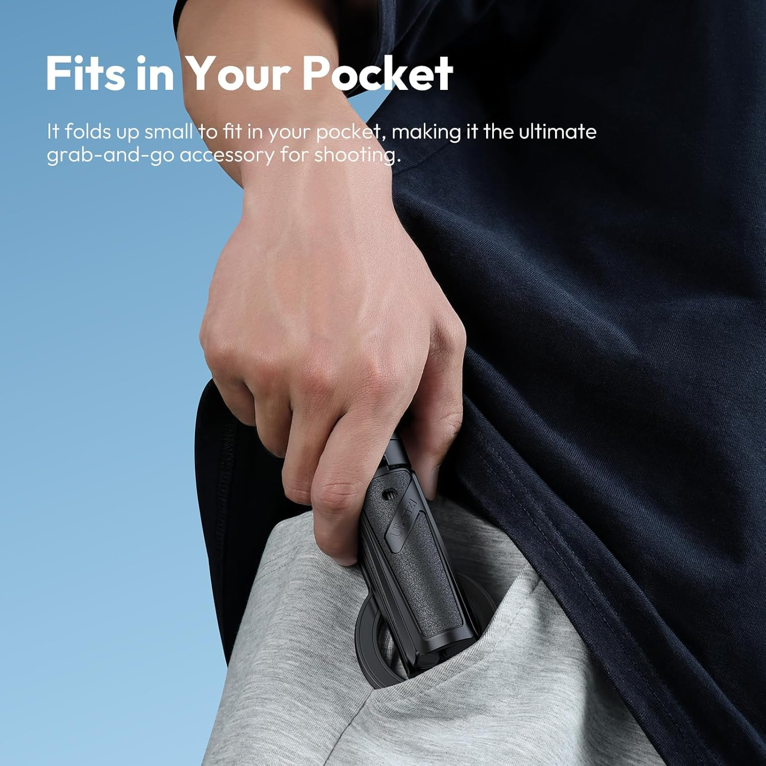 Una mano metiendo un estabilizador de cámara negro y compacto en un bolsillo gris. Fondo de cielo azul con texto 'Fits in Your Pocket'.