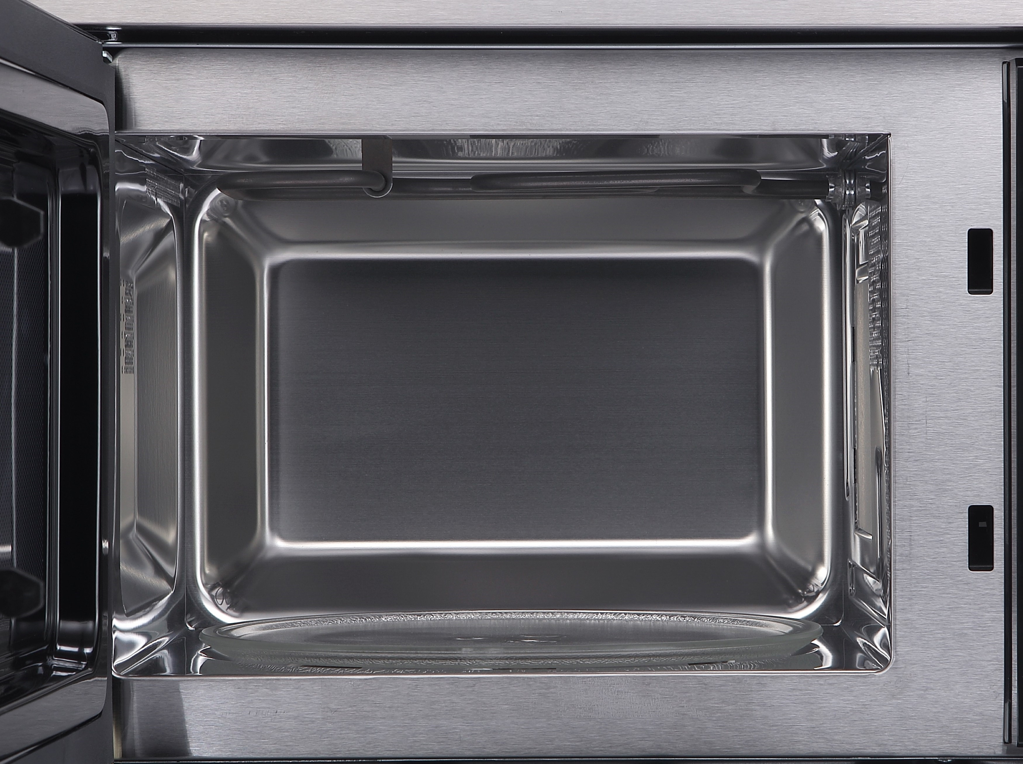 Inside view of a microwave oven. Stainless steel interior with a glass plate. The door is open.