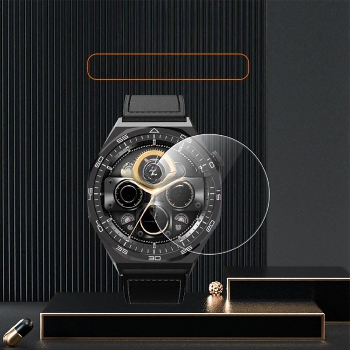 Uno smartwatch nero con una protezione per lo schermo trasparente è esposto su una piattaforma nera. Una capsula dorata a sinistra.