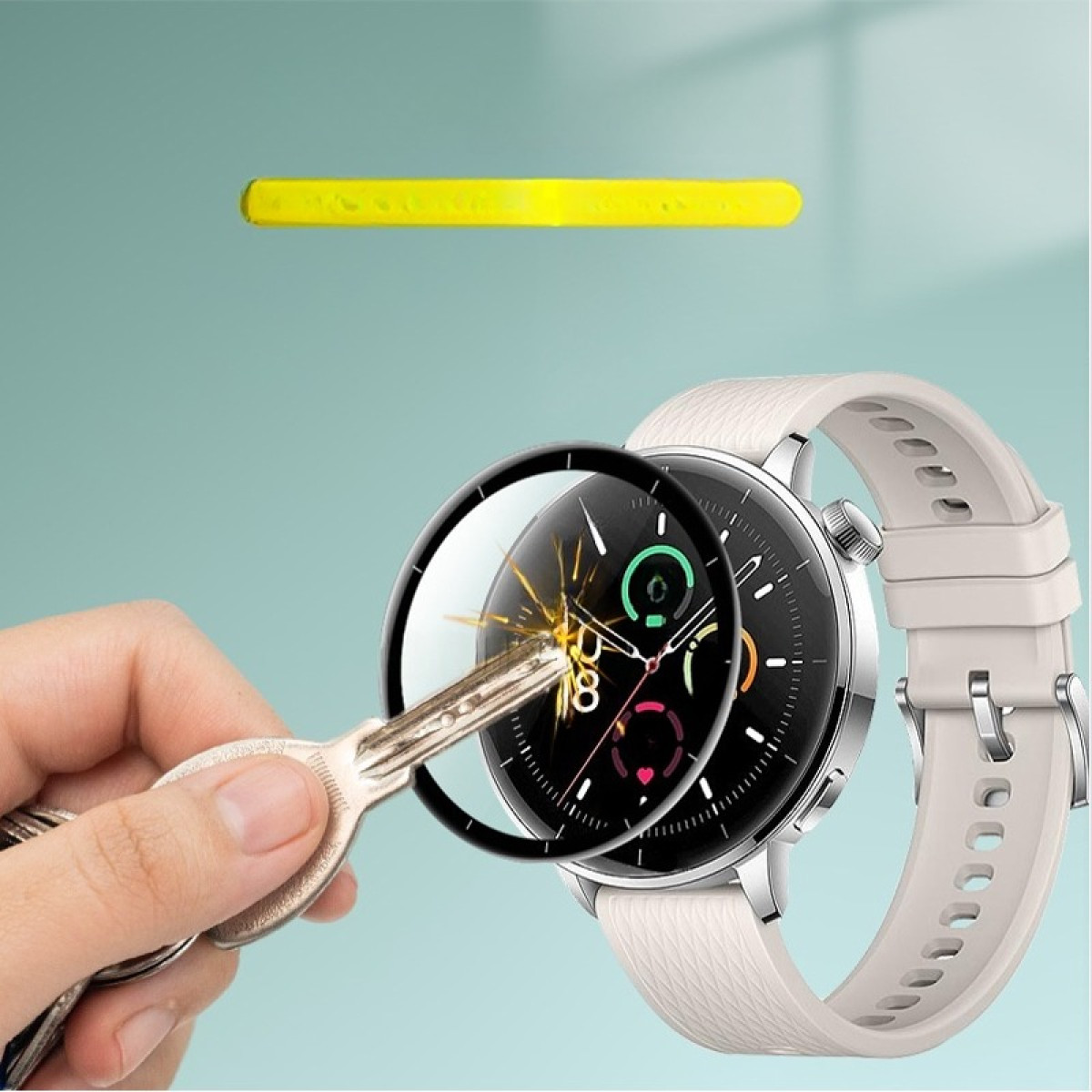 Una mano tiene una chiave vicino a uno smartwatch. L'orologio ha un quadrante nero e un cinturino bianco. C'è una barra gialla sopra.