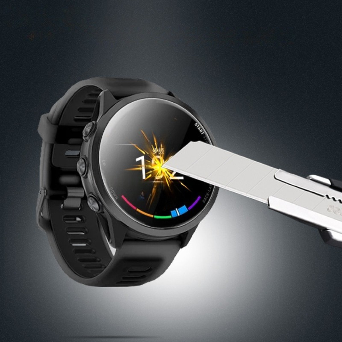 Uno smartwatch nero viene tagliato con un taglierino. L'orologio mostra un'ora digitale e un anello colorato in basso.