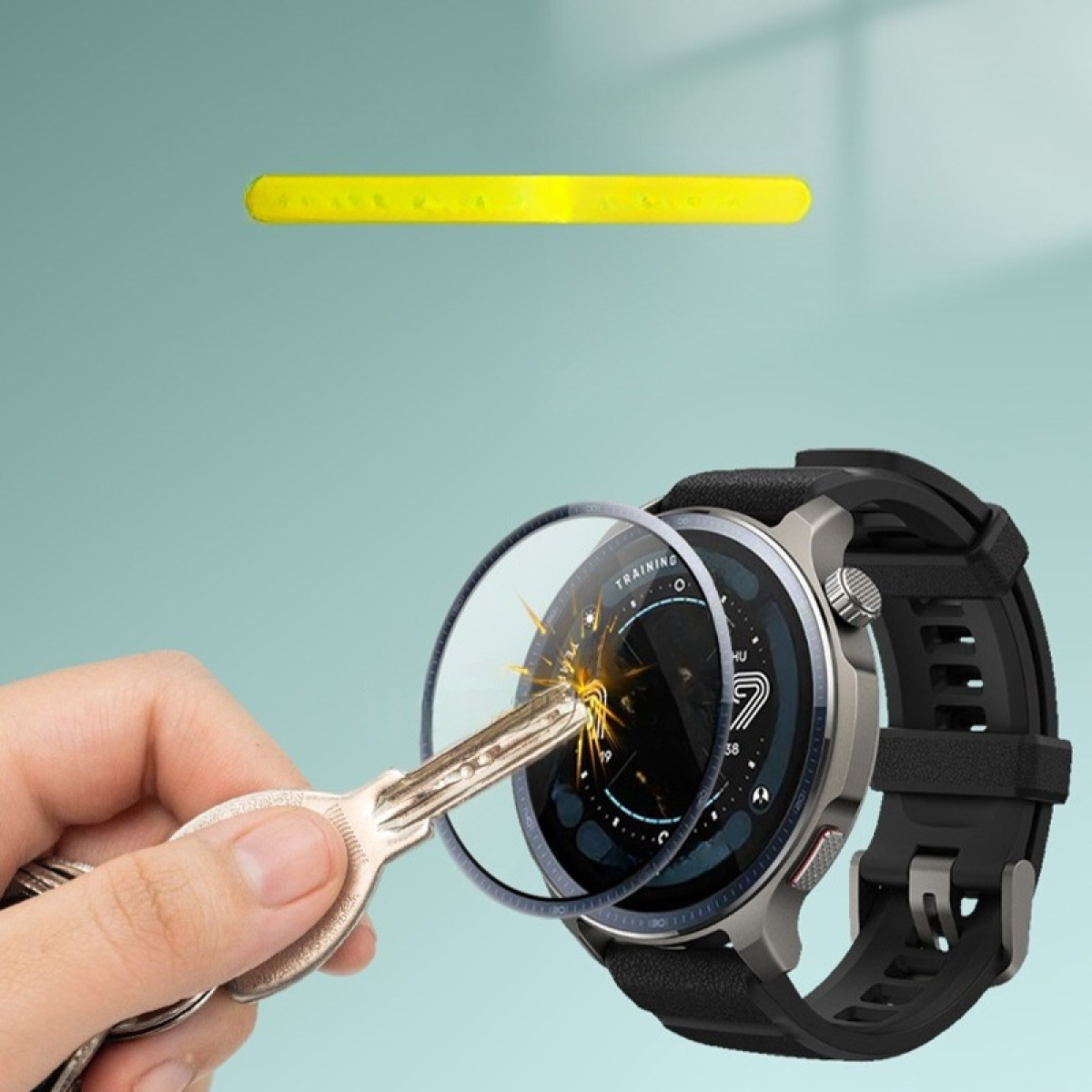 Una mano con una chiave sta per graffiare lo schermo di uno smartwatch. Una barra gialla è sopra. Lo sfondo è azzurro.
