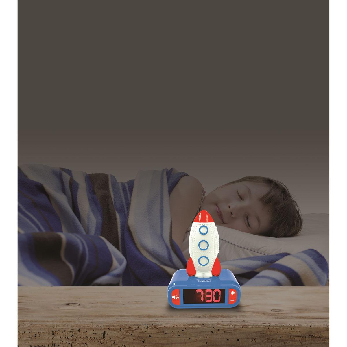 Un niño duerme en una cama, cubierto con una manta. Un despertador con forma de cohete está en la mesita de noche de madera, mostrando las 7:30.