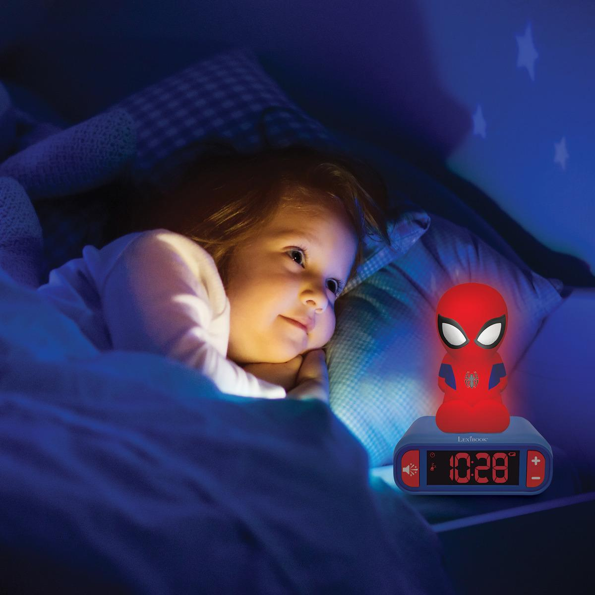 Un niño yace en la cama, iluminado por un reloj de Spider-Man. El reloj muestra la hora. Estrellas proyectadas en la pared.