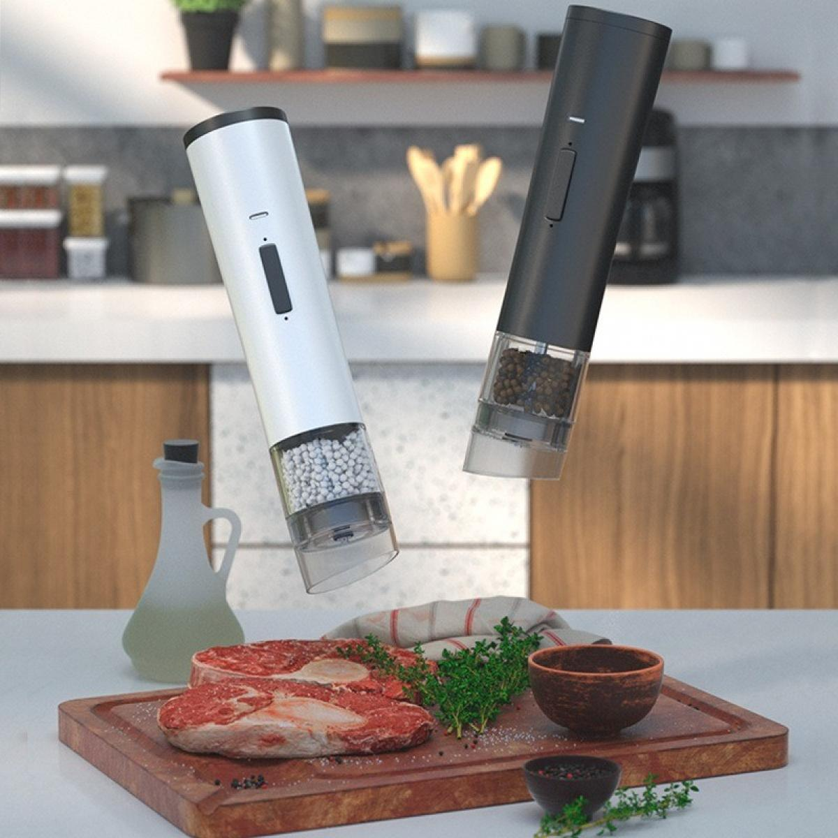 Zwei elektrische Mühlen über einem Holzbrett mit Steak, Kräutern und einer kleinen Schüssel. Küchenumgebung.