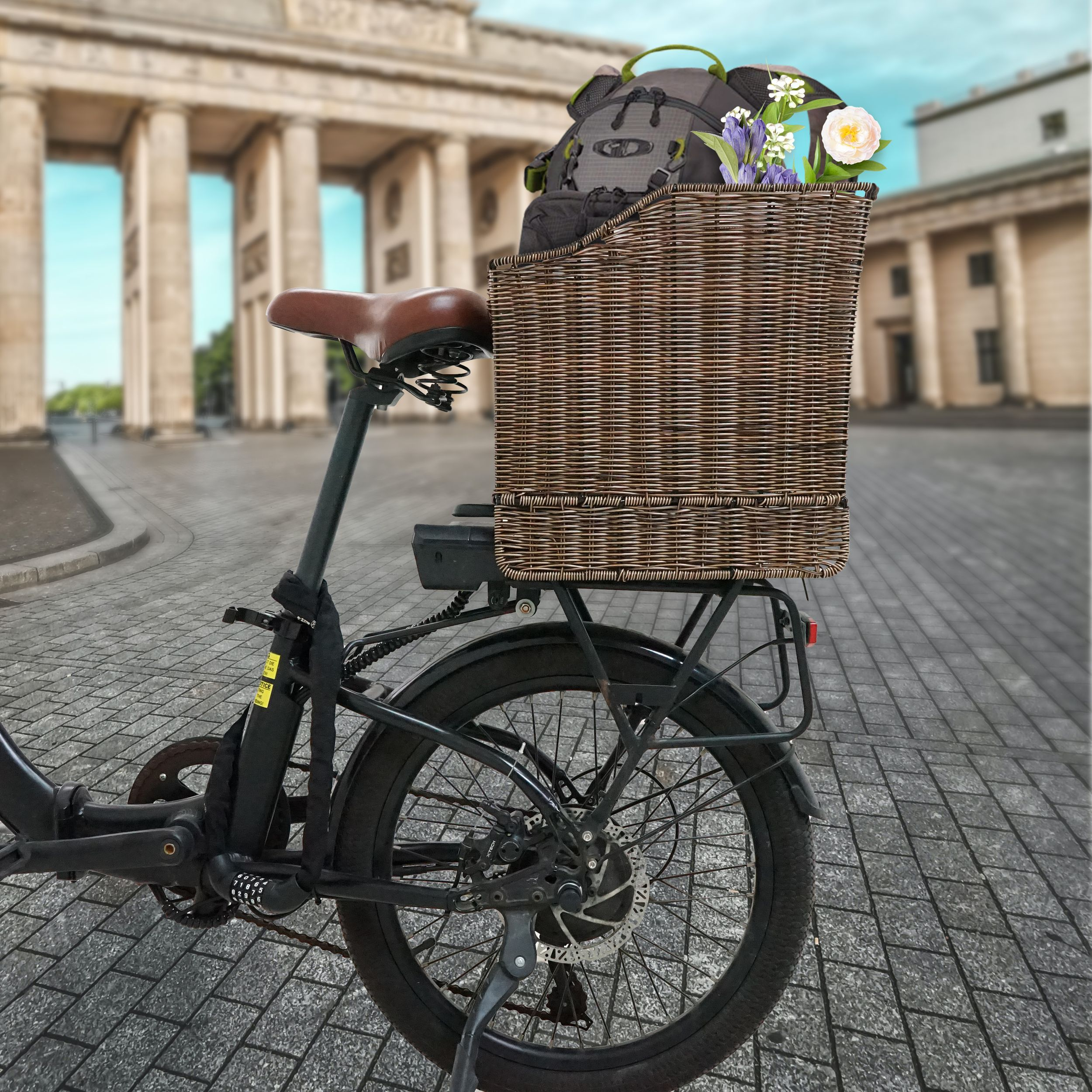 Schwarzes Fahrrad mit Blumenkorb und Rucksack vor einem Wahrzeichen.