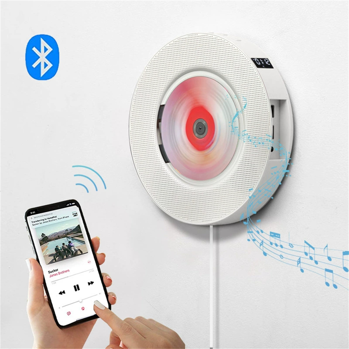 Ein weißer CD-Player an der Wand spielt eine Disc. Ein Telefon zeigt Musik an, verbunden über Bluetooth. Eine Hand berührt den Bildschirm.