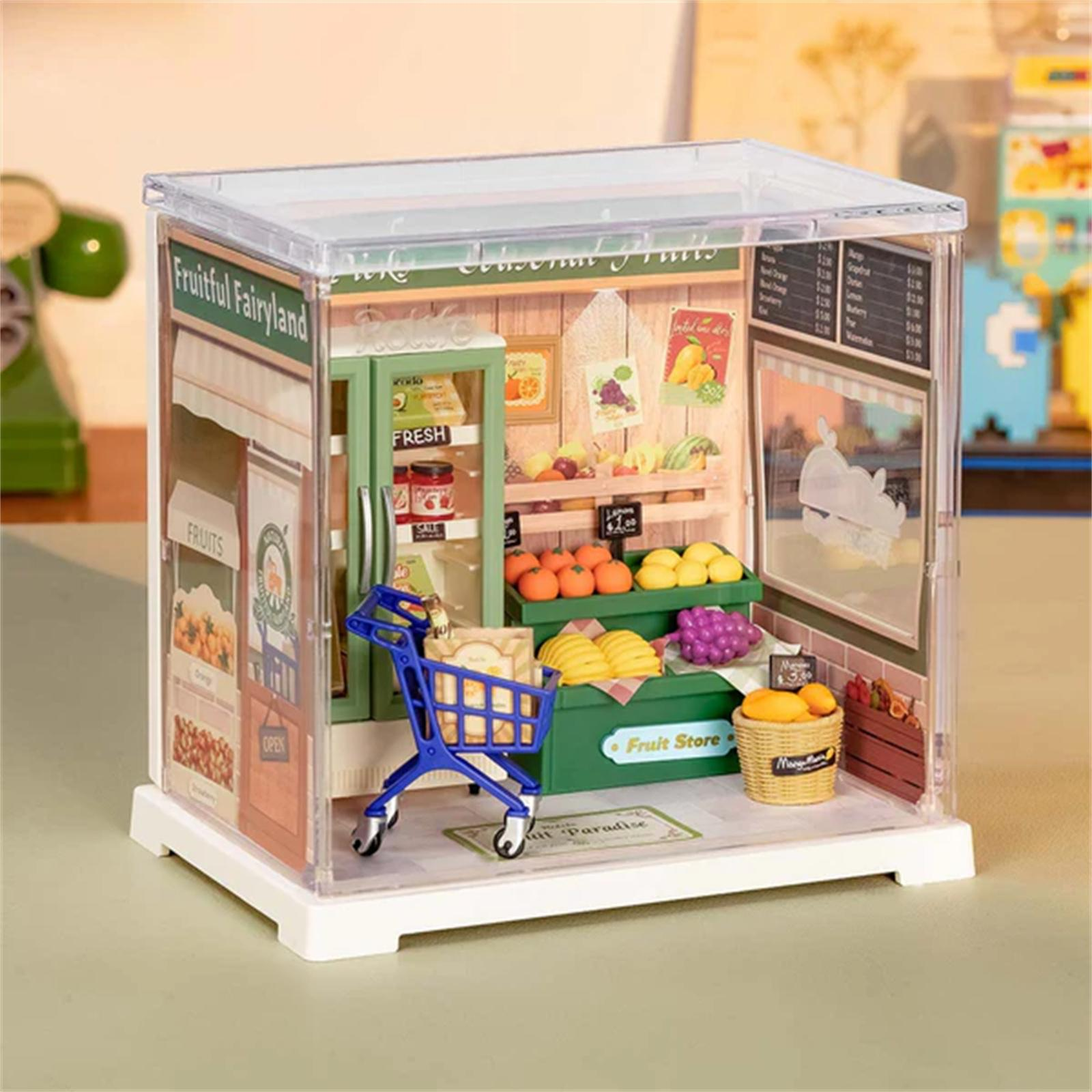 Miniatur-Obstladen-Modell. Enthält einen blauen Einkaufswagen, Früchte und Schilder. Der Laden trägt den Titel 'Fruitful Fairyland'.
