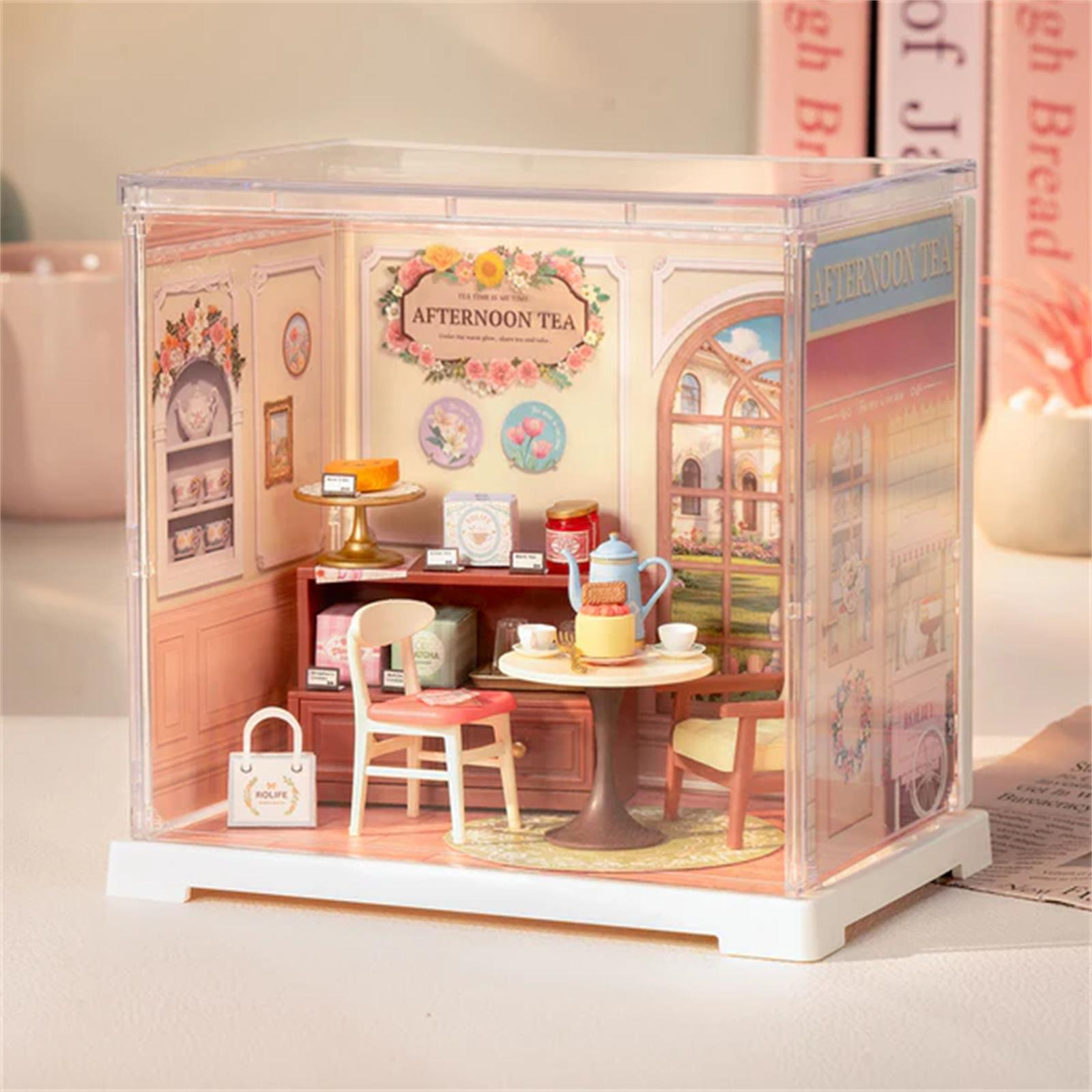 Miniatur-Nachmittagstee-Szene in einer durchsichtigen Box. Mit Tisch, Stühlen, Kuchen, Teeservice und Wanddekorationen.