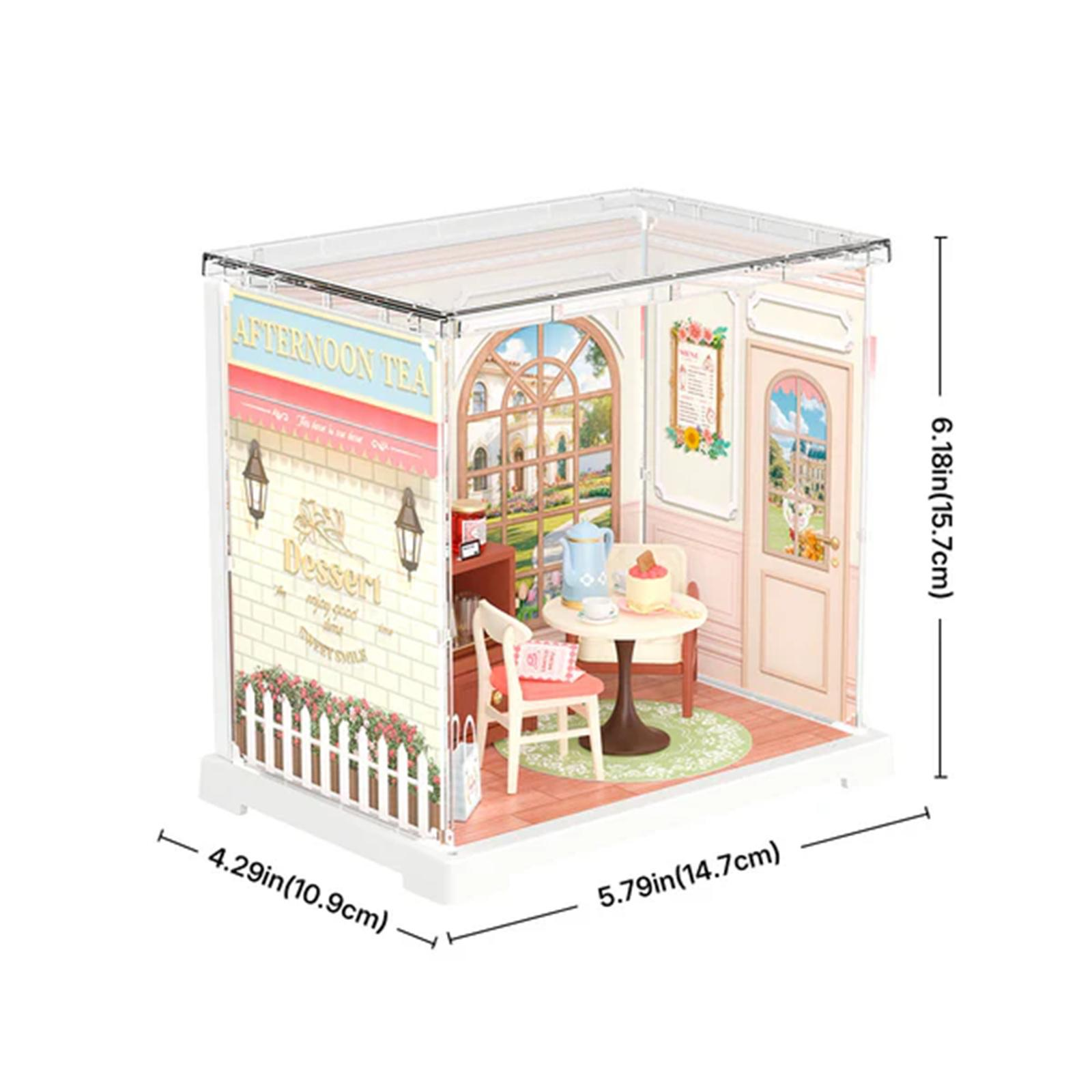 Miniatur-Café-Szene. Enthält einen Tisch, Stühle, Kuchen, Teeservice und eine Tür. Die Wände sind mit Blumen geschmückt.