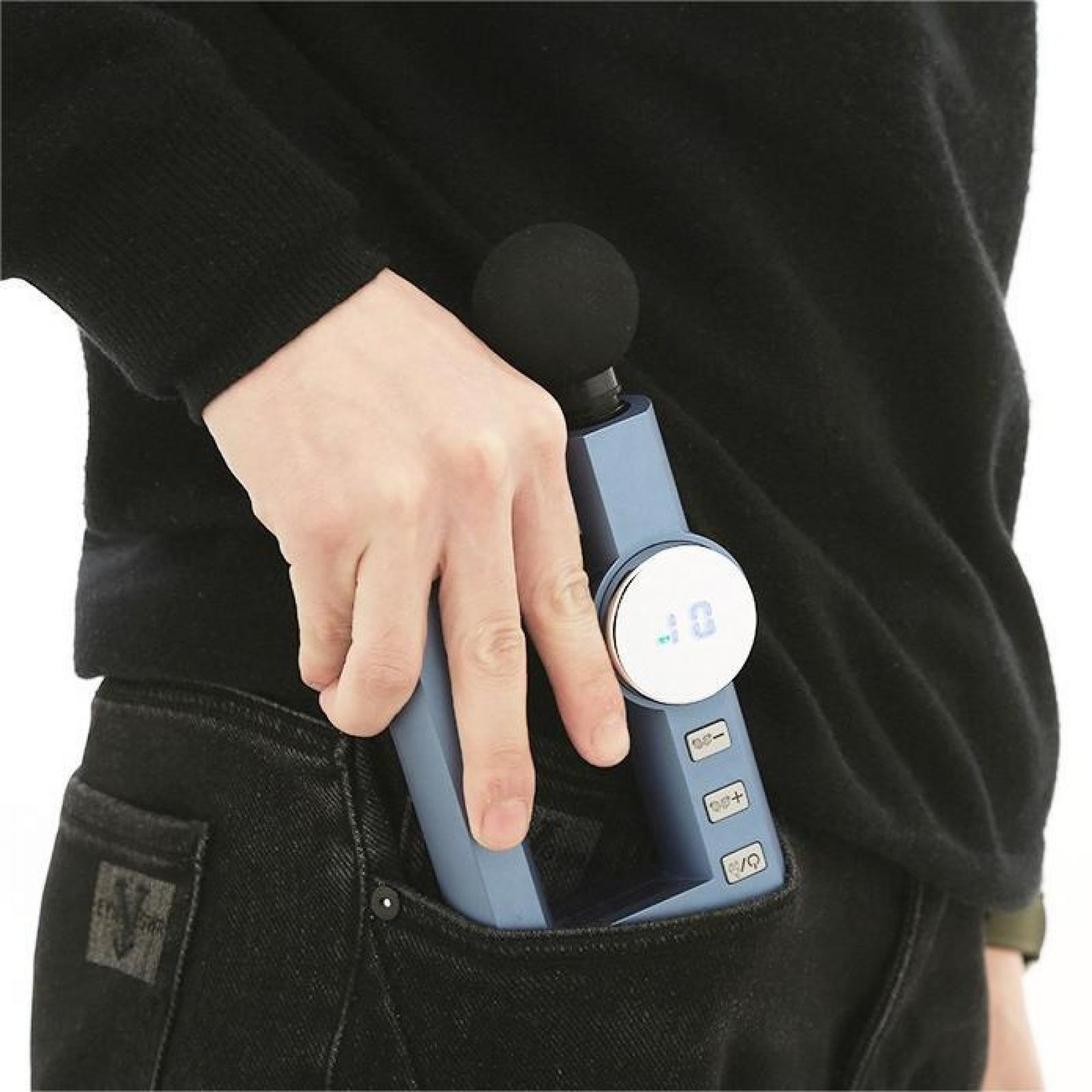 Eine Person hält eine blaue Massagepistole in ihrer Tasche. Das schwarze Gerät hat einen runden schwarzen Kopf und Knöpfe.