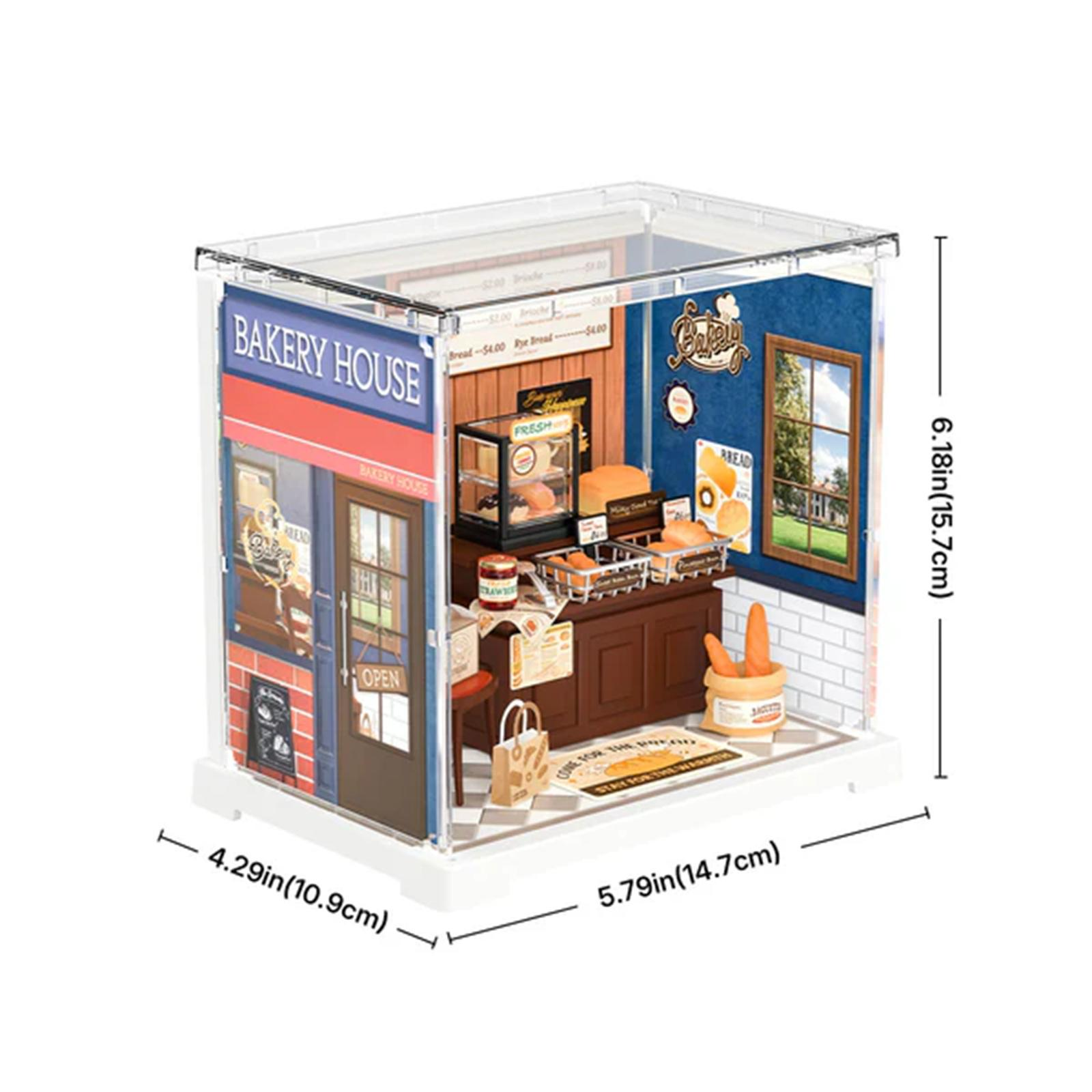 Ein Miniatur-Bäckerei-Diorama. Es hat eine blaue Fassade, eine braune Tür und einen Innenraum mit Brotauslagen und einem kleinen Tisch.