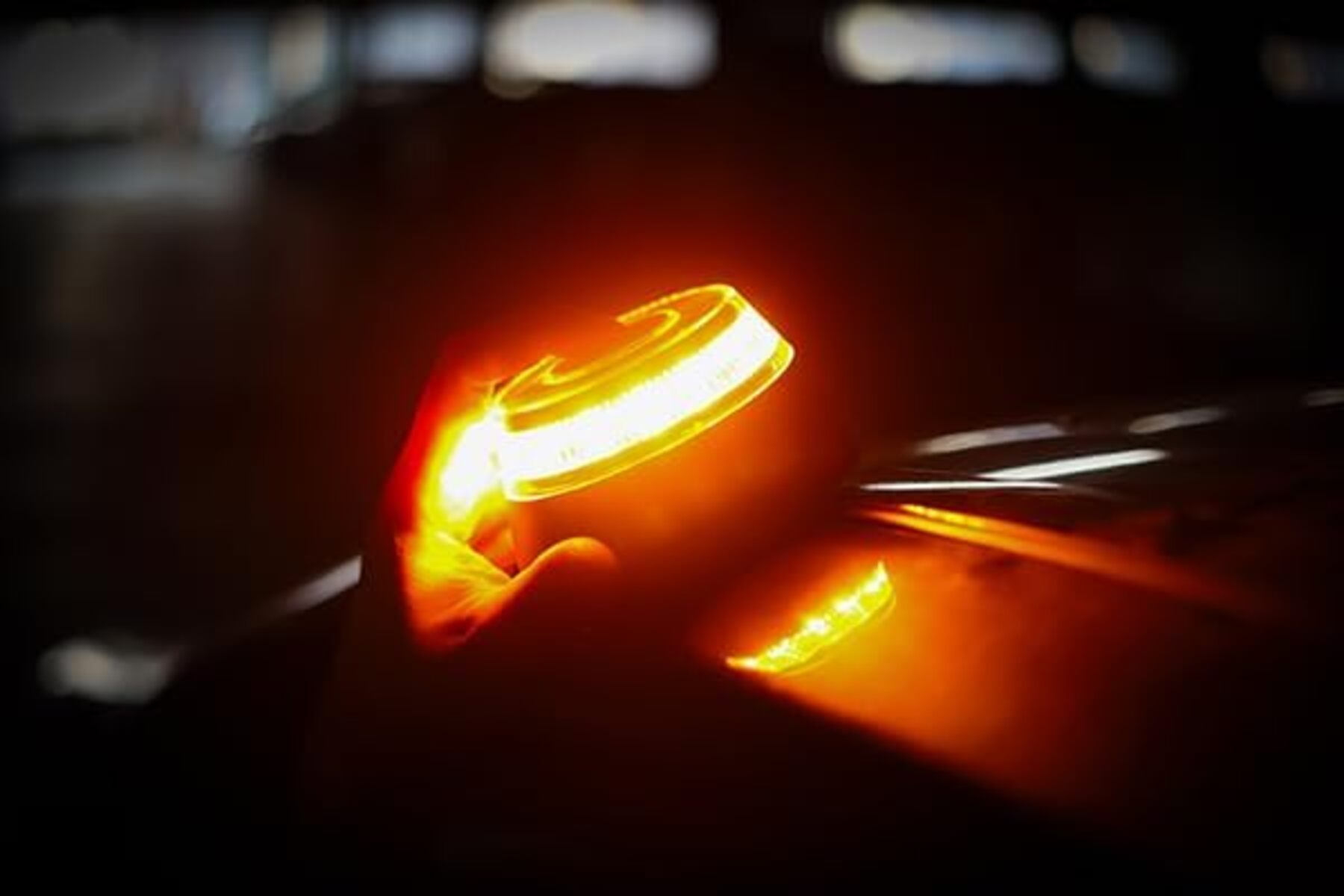 Una mano sostiene una luz circular brillante. La luz es de color amarillo-naranja brillante sobre un fondo oscuro.
