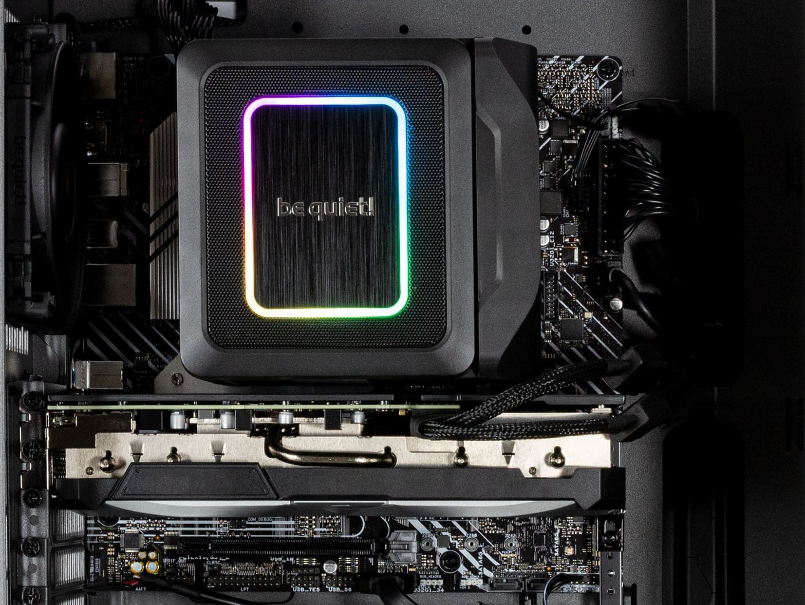 Componenti PC, dissipatore CPU con RGB, scheda grafica e scheda madre visibili. Il logo be quiet! è illuminato.
