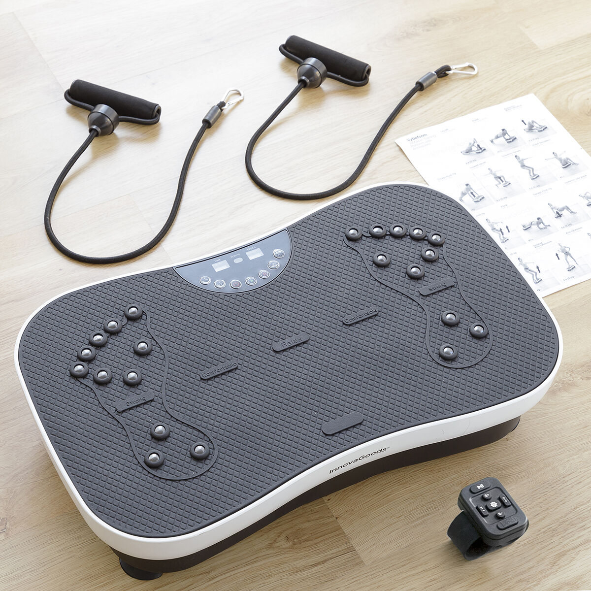 Plateforme vibrante avec poignées, télécommande et guide d'exercices. Plateforme grise avec repères de pieds, bord blanc et sol en bois.