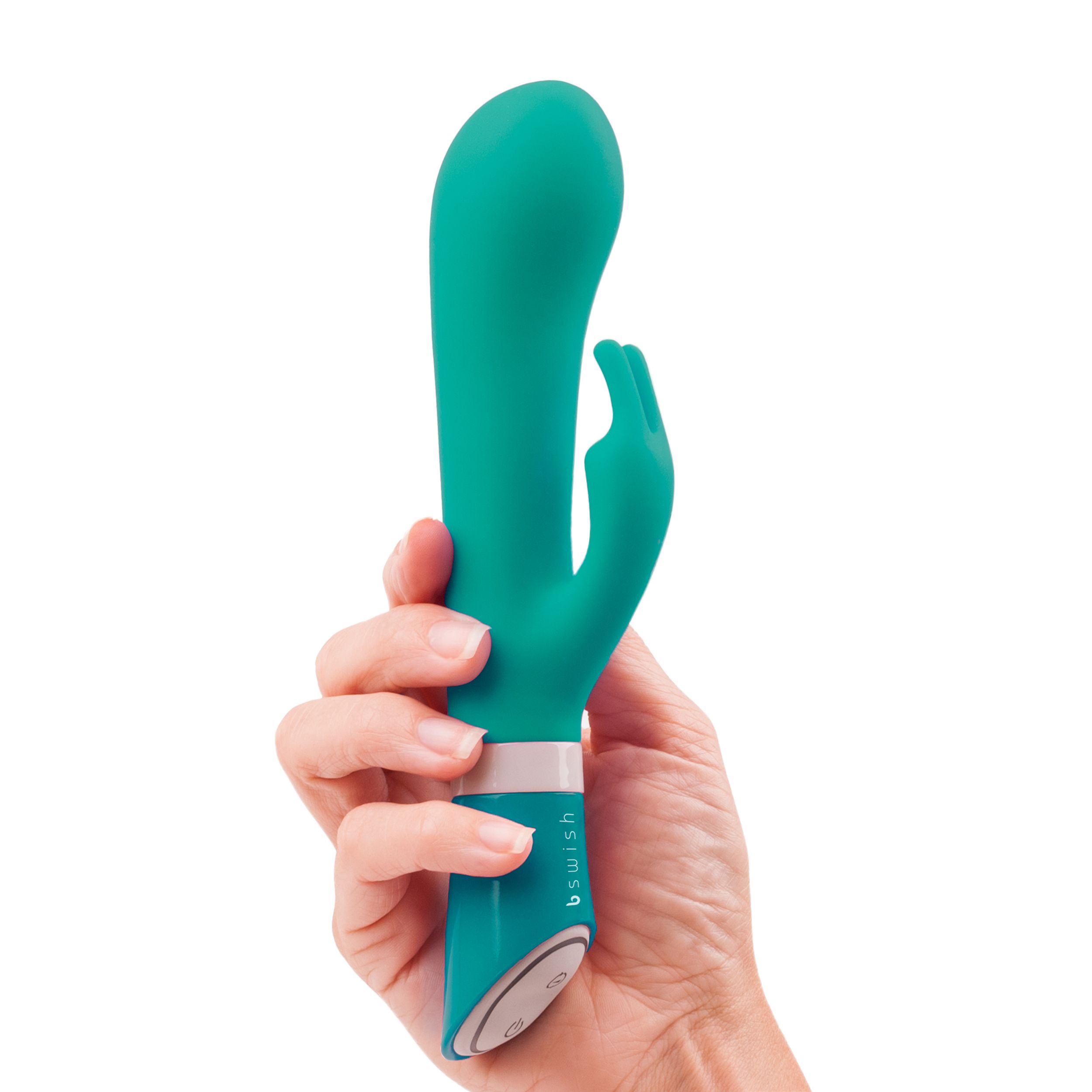 Una mano sostiene un vibrador verde azulado sobre un fondo blanco. El vibrador tiene la etiqueta 'b swish'.