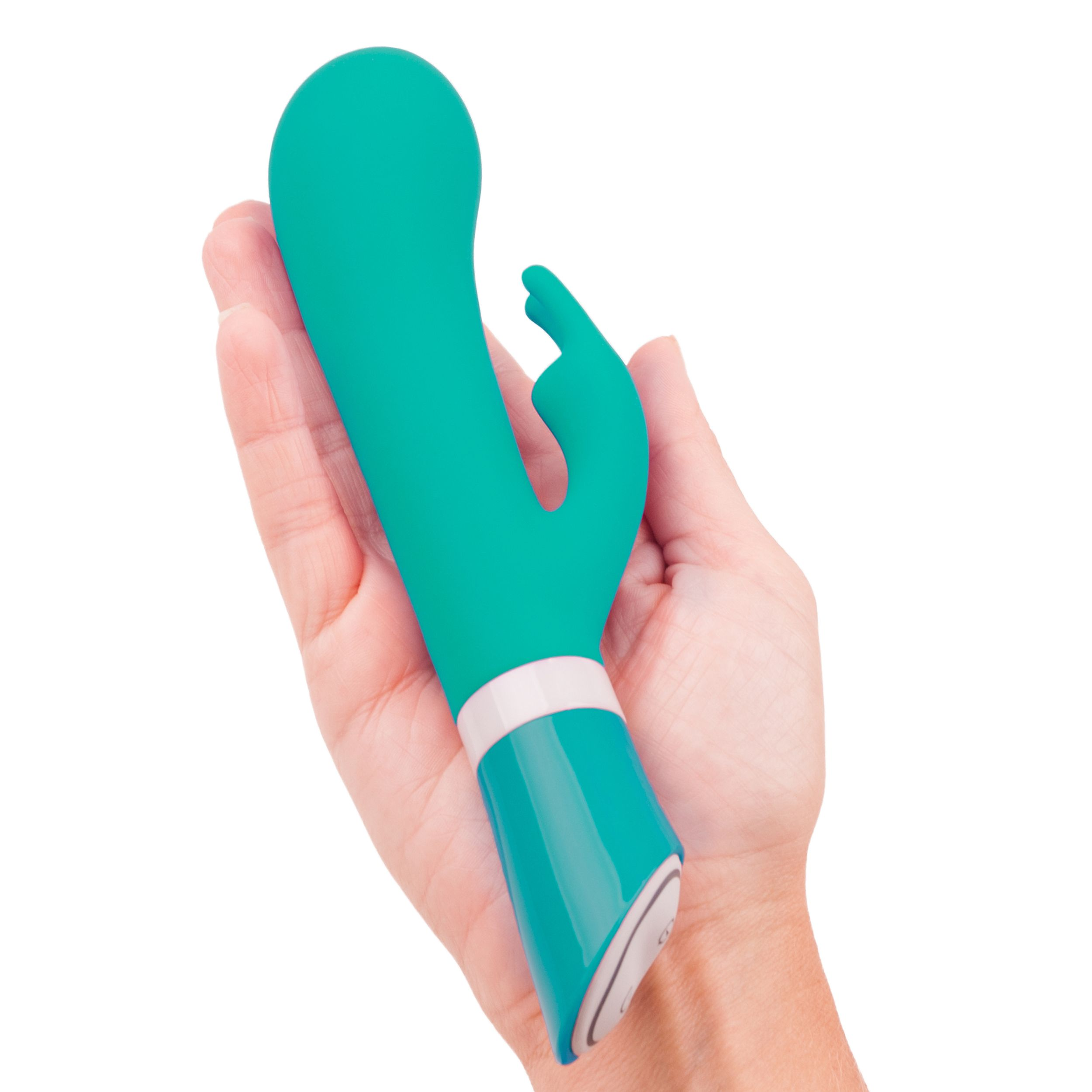 Un vibrador verde azulado se sostiene en una mano. Tiene un diseño curvo y una base blanca y azul. El fondo es blanco.