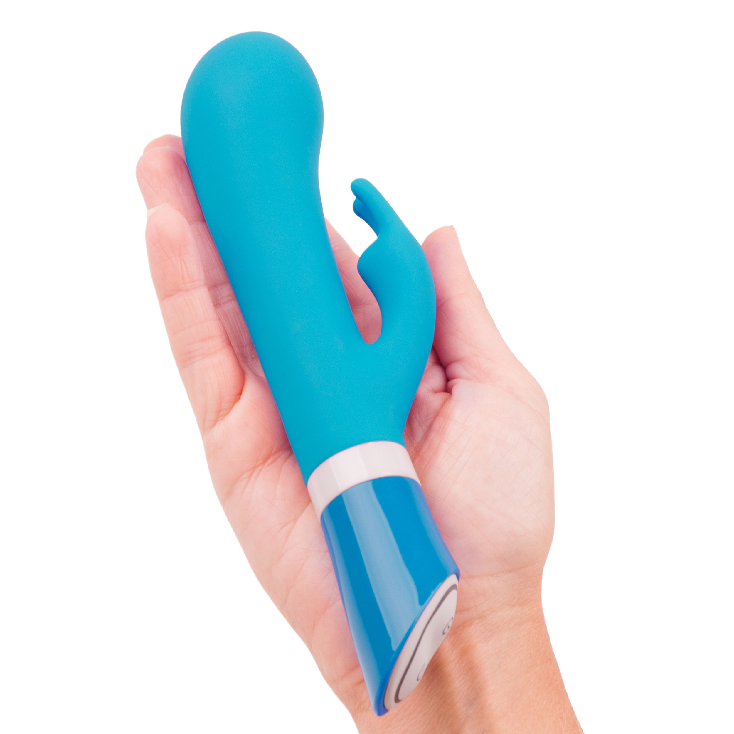 Una mano sostiene un vibrador de color verde azulado. El vibrador tiene forma curva y está sobre un fondo blanco.