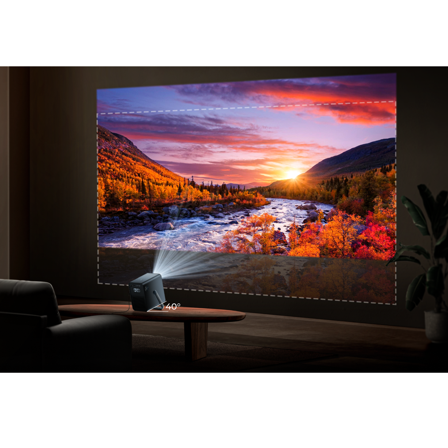 Un proyector muestra una puesta de sol sobre un río. Un proyector negro está sobre una mesa. Las paredes son marrones oscuras.
