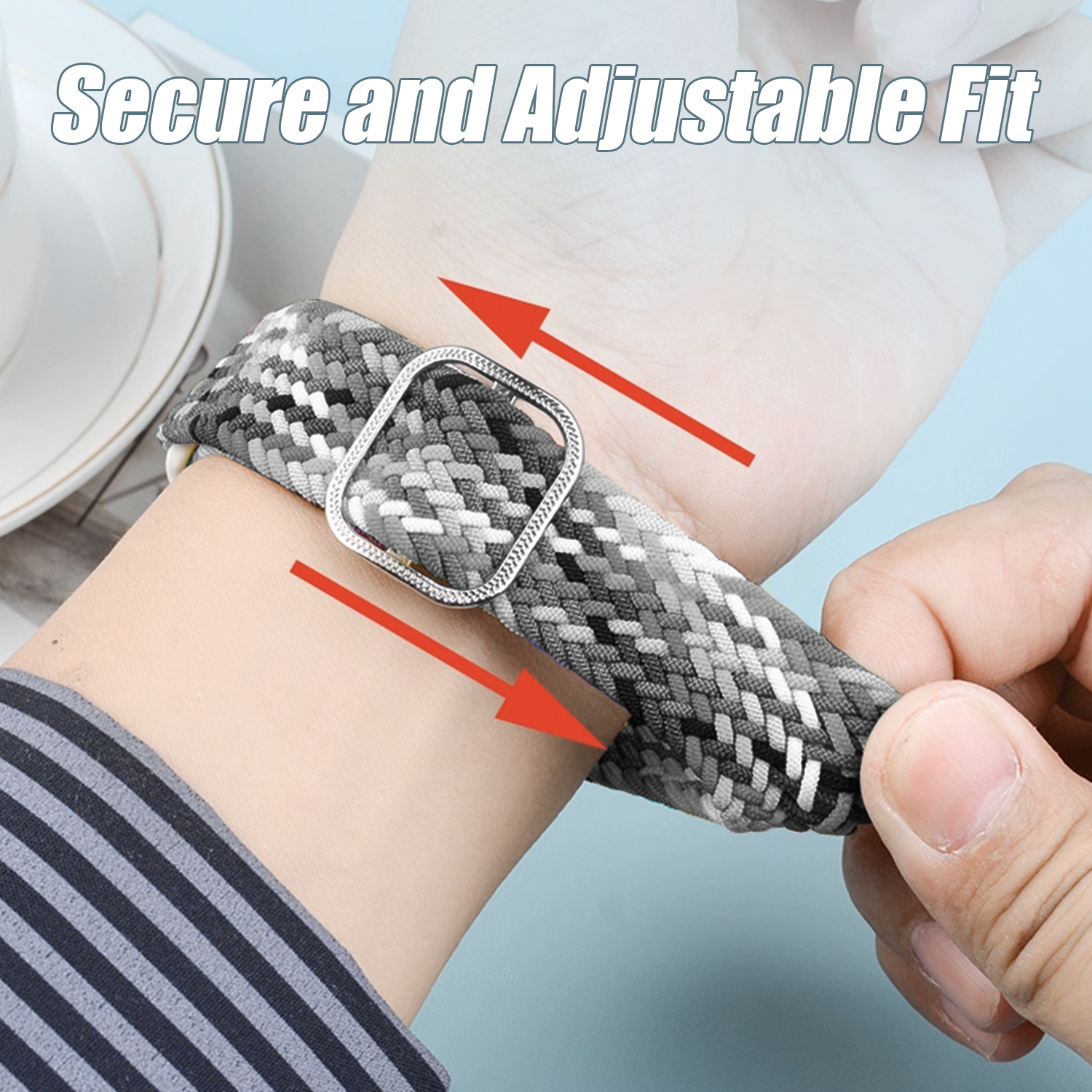 Ręka reguluje szaro-biały pleciony pasek do zegarka na nadgarstku. Strzałki wskazują punkty regulacji. Tekst: 'Bezpieczne i regulowane dopasowanie'.
