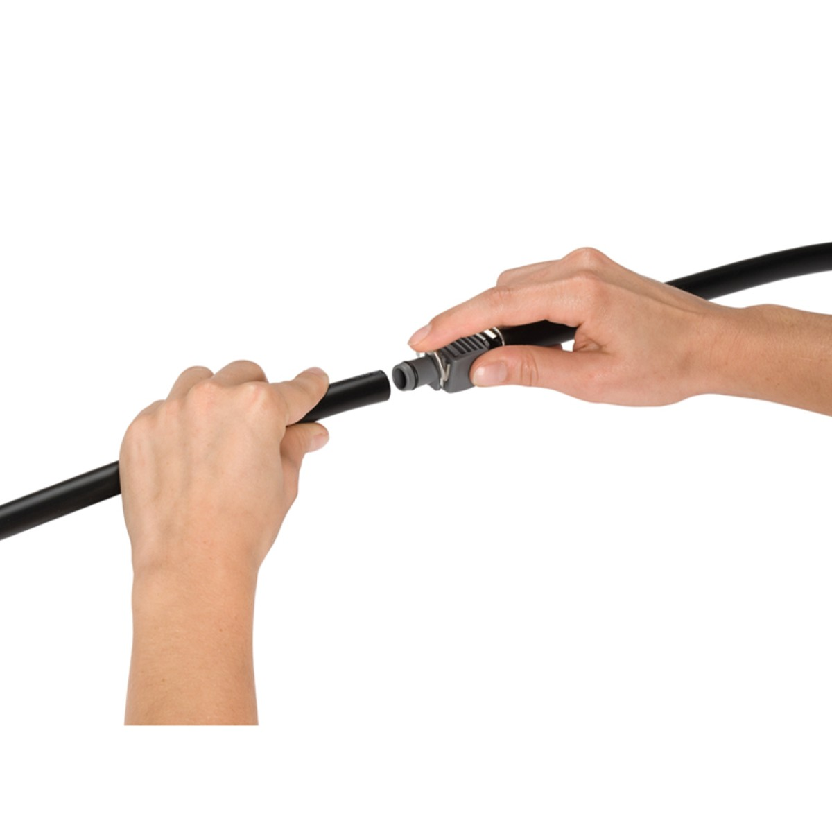 Manos conectando una manguera negra a un conector gris. Fondo blanco.