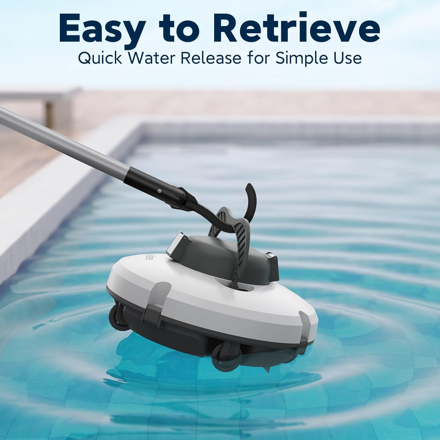 A pool cleaner is being retrieved from the water. It is white and gray, with a handle and wheels. Water is blue.
