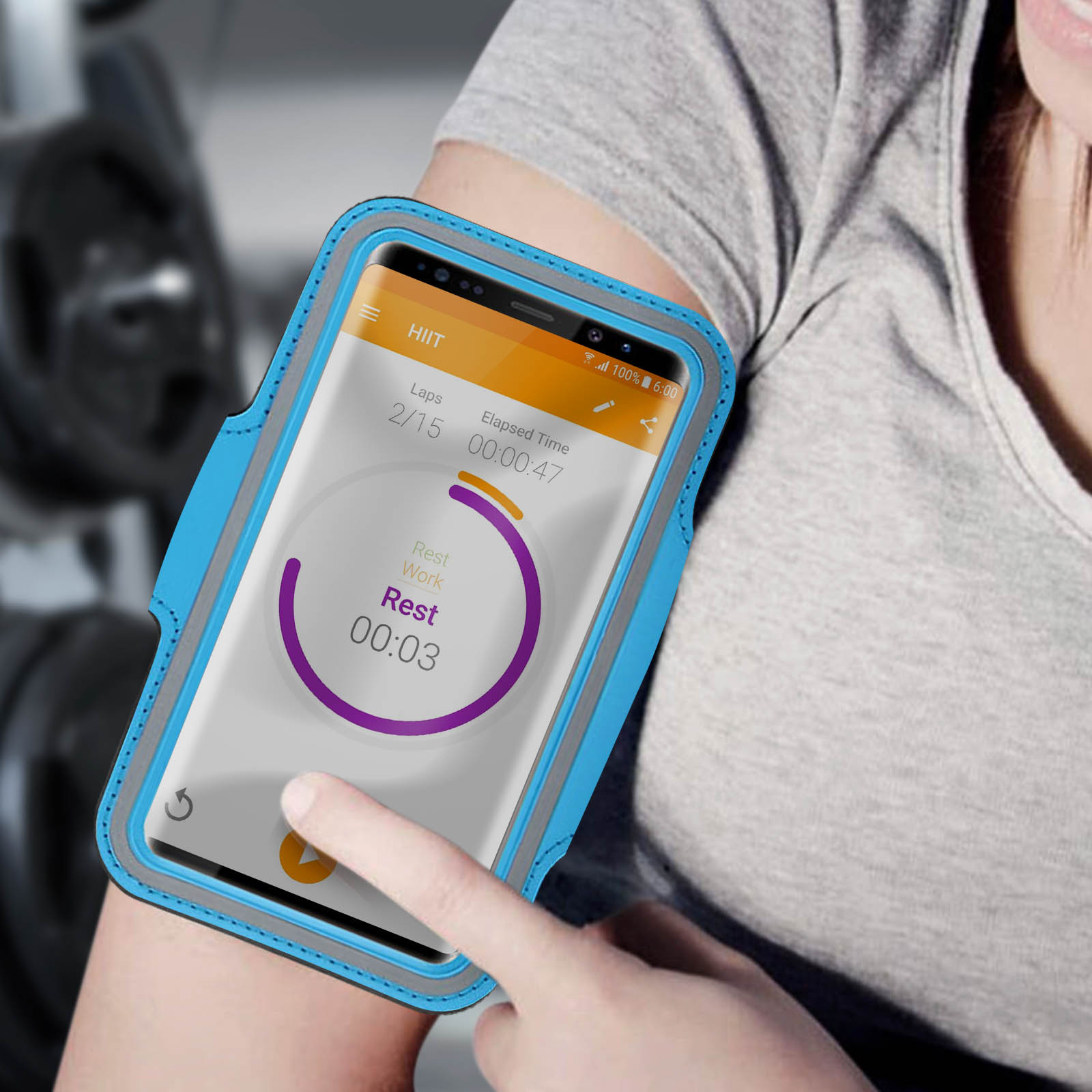 Le bras d'une personne avec un téléphone dans un brassard bleu affichant une application d'entraînement HIIT. L'écran affiche le temps, les tours et le temps de repos.