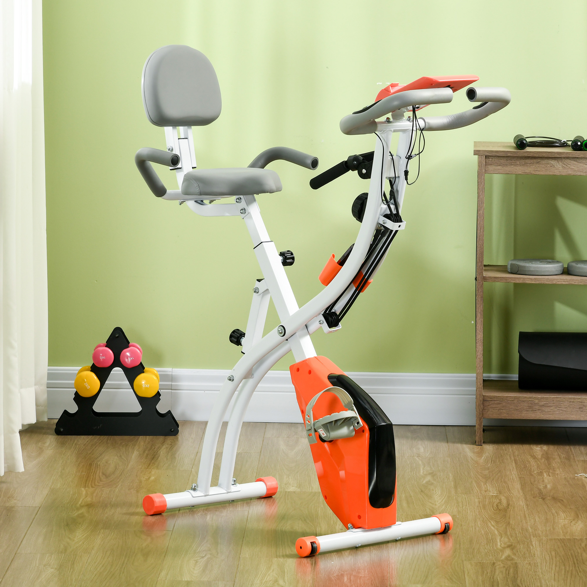 Una cyclette con sedile grigio e inserti arancioni si trova in una stanza. Manubri e una mensola sullo sfondo.