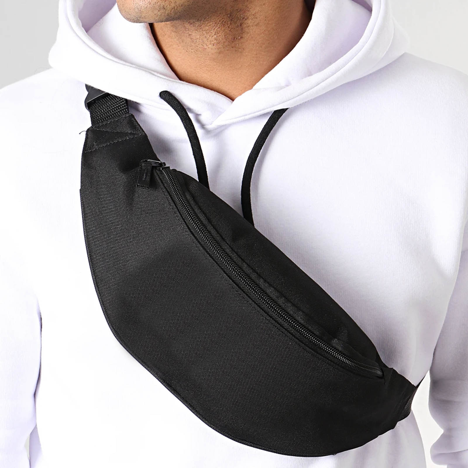 Eine Person trägt einen weißen Kapuzenpullover mit einer schwarzen Bauchtasche. Die Tasche ist schwarz.