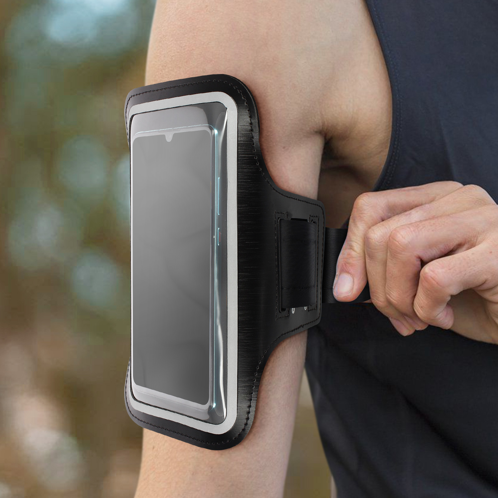 Une personne portant un brassard noir avec un téléphone. Le bras de la personne est au premier plan. Arrière-plan flou.