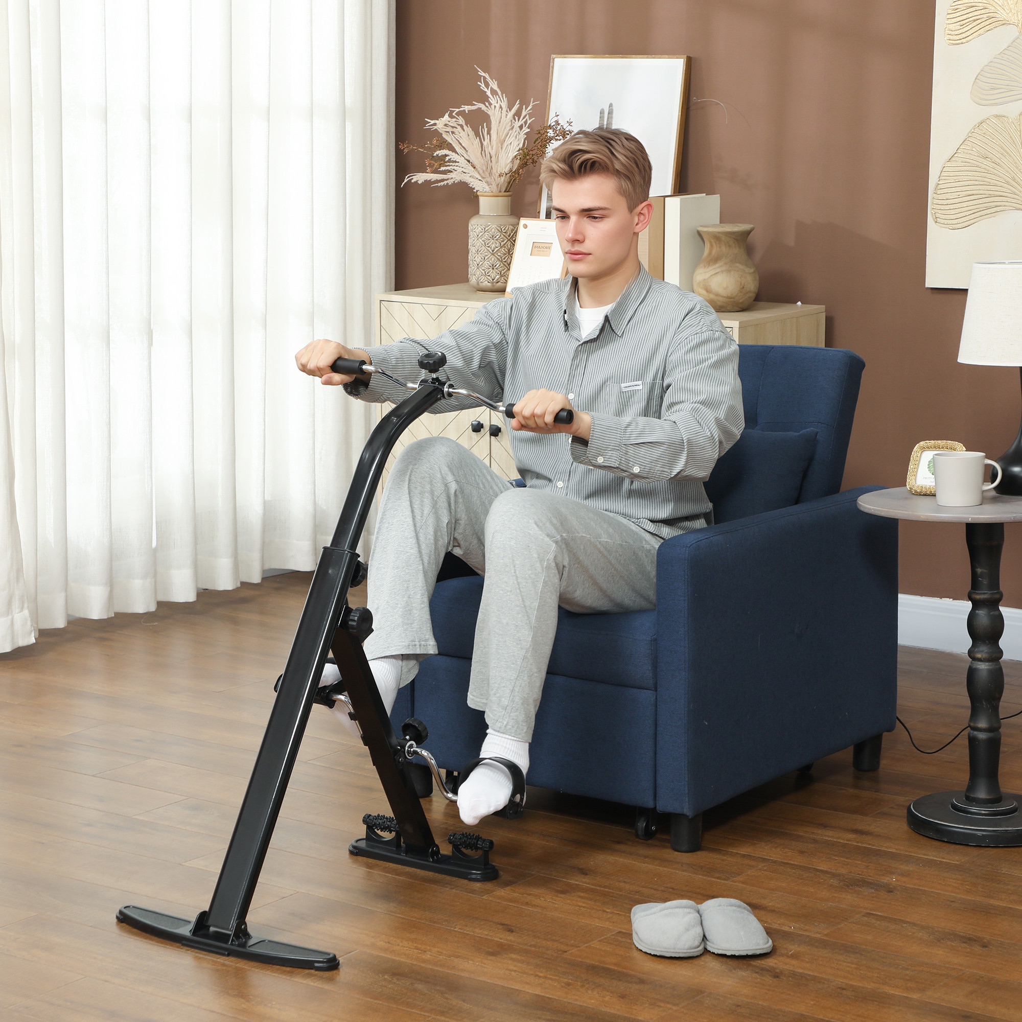 Un uomo in pigiama usa una cyclette seduto in una poltrona blu nel suo soggiorno.