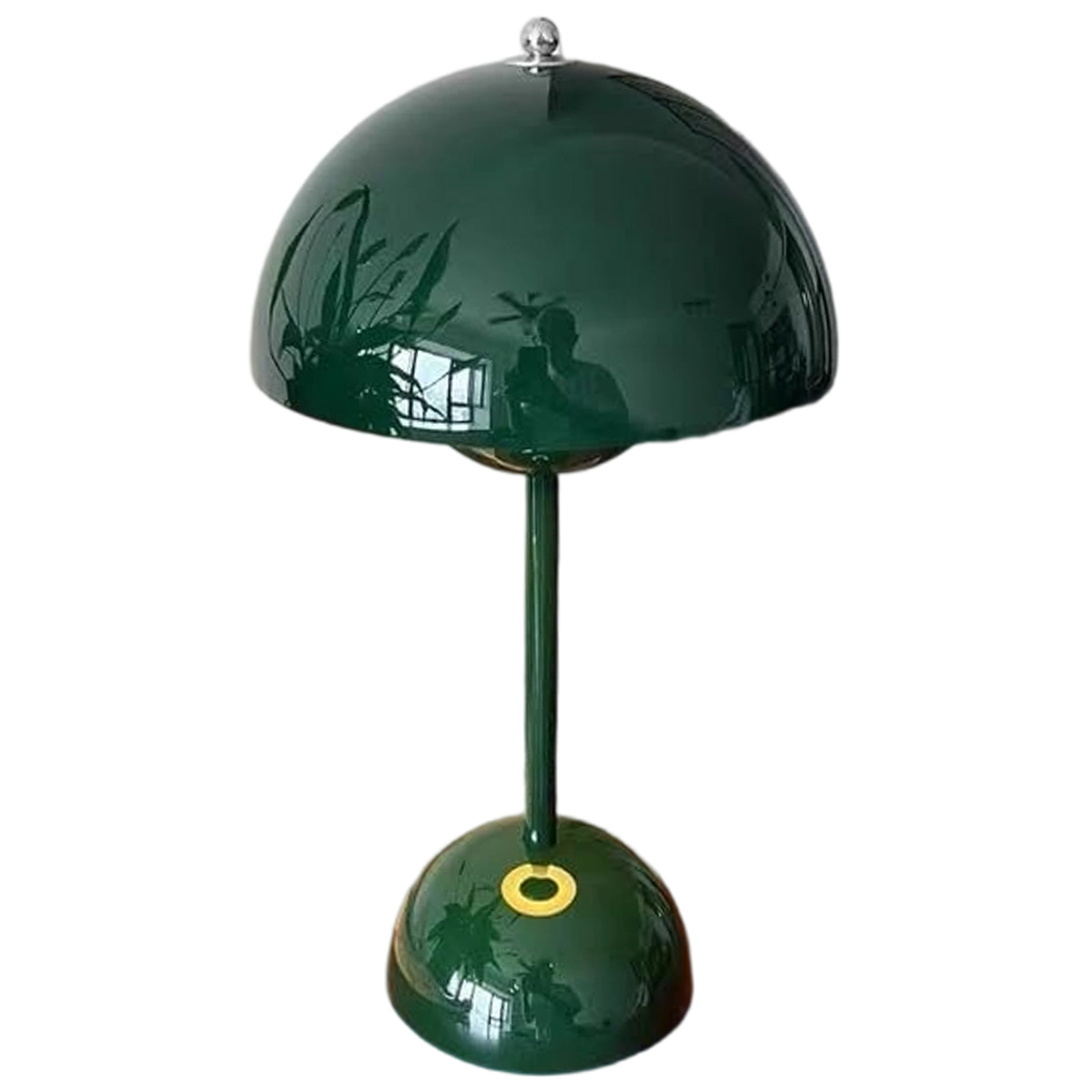 Eine grüne Tischlampe mit rundem Schirm und Sockel, einem langen Stiel. Die Lampe spiegelt ihre Umgebung wider.