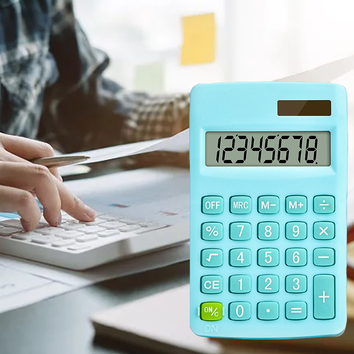 Eine Person, die einen Taschenrechner und eine Computertastatur benutzt. Ein hellblauer Rechner zeigt '12345678'. Ein Stift liegt auf dem Tisch.