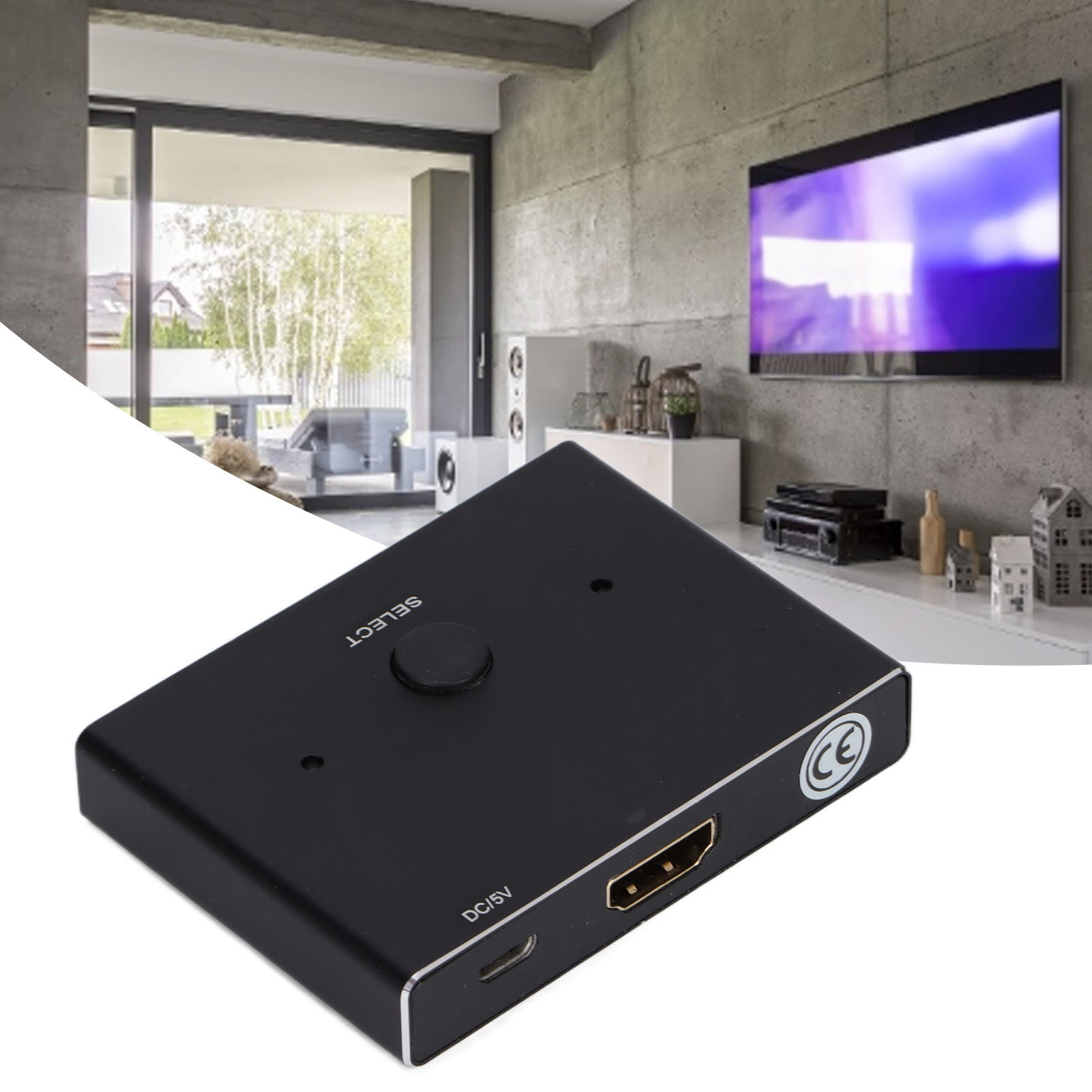 Ein schwarzes elektronisches Gerät mit Knöpfen und Anschlüssen liegt auf einer weißen Oberfläche. Im Hintergrund ist ein Fernseher an einer Betonwand montiert.