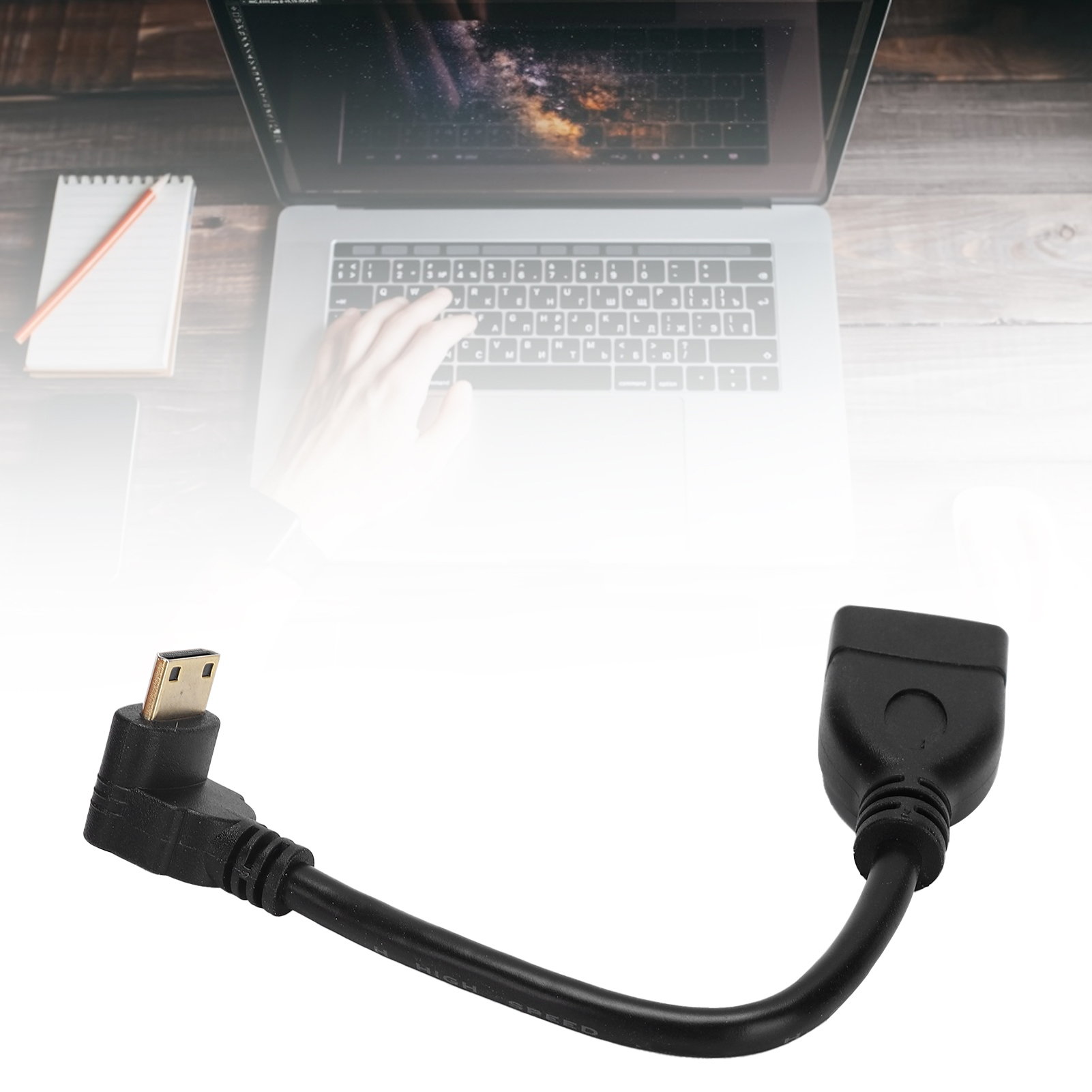 Ein schwarzes Adapterkabel mit Steckern, ein Laptop mit Hand auf der Tastatur, Notizblock und Bleistift auf einem Holztisch.